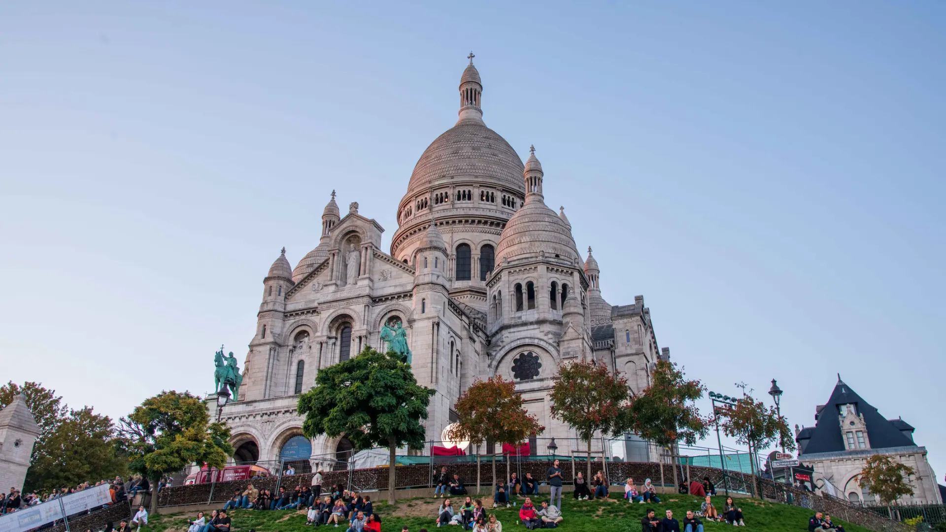 People sitting on the grass in front of Sacre Coeur Church.