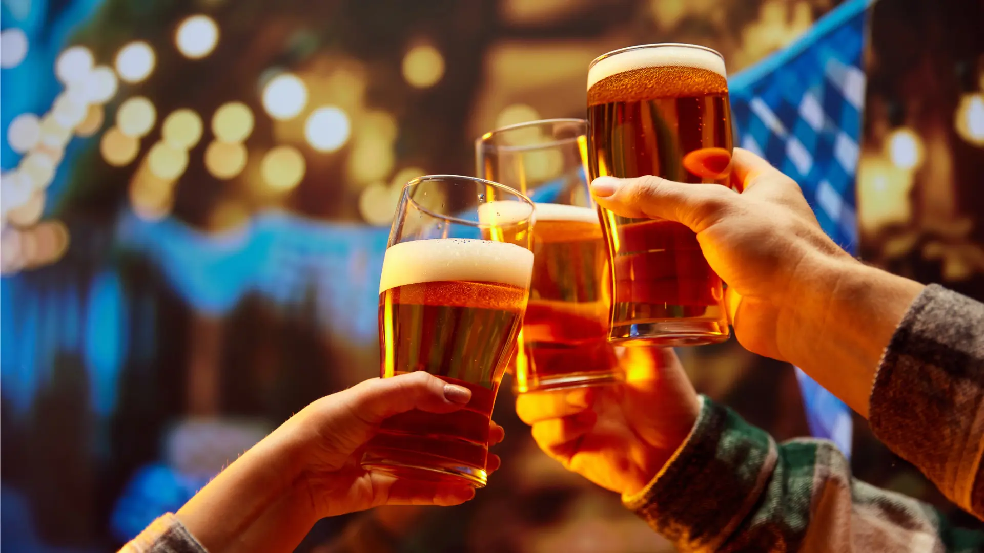 Three hands holding glasses filled with beer.
