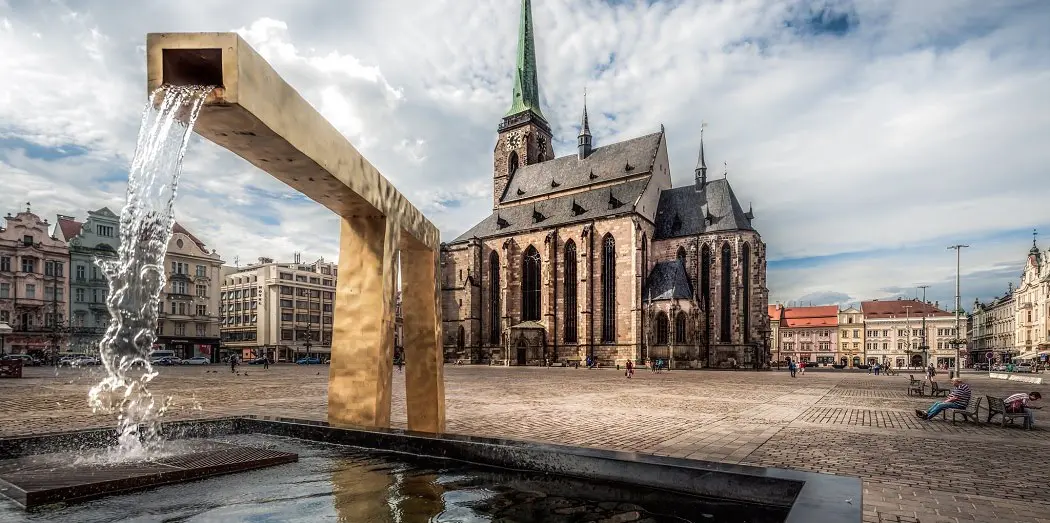 Plzen's main square, Namesti Republiky, with a water fountain in the foreground and the cathedral of St Bartholemew in the background.