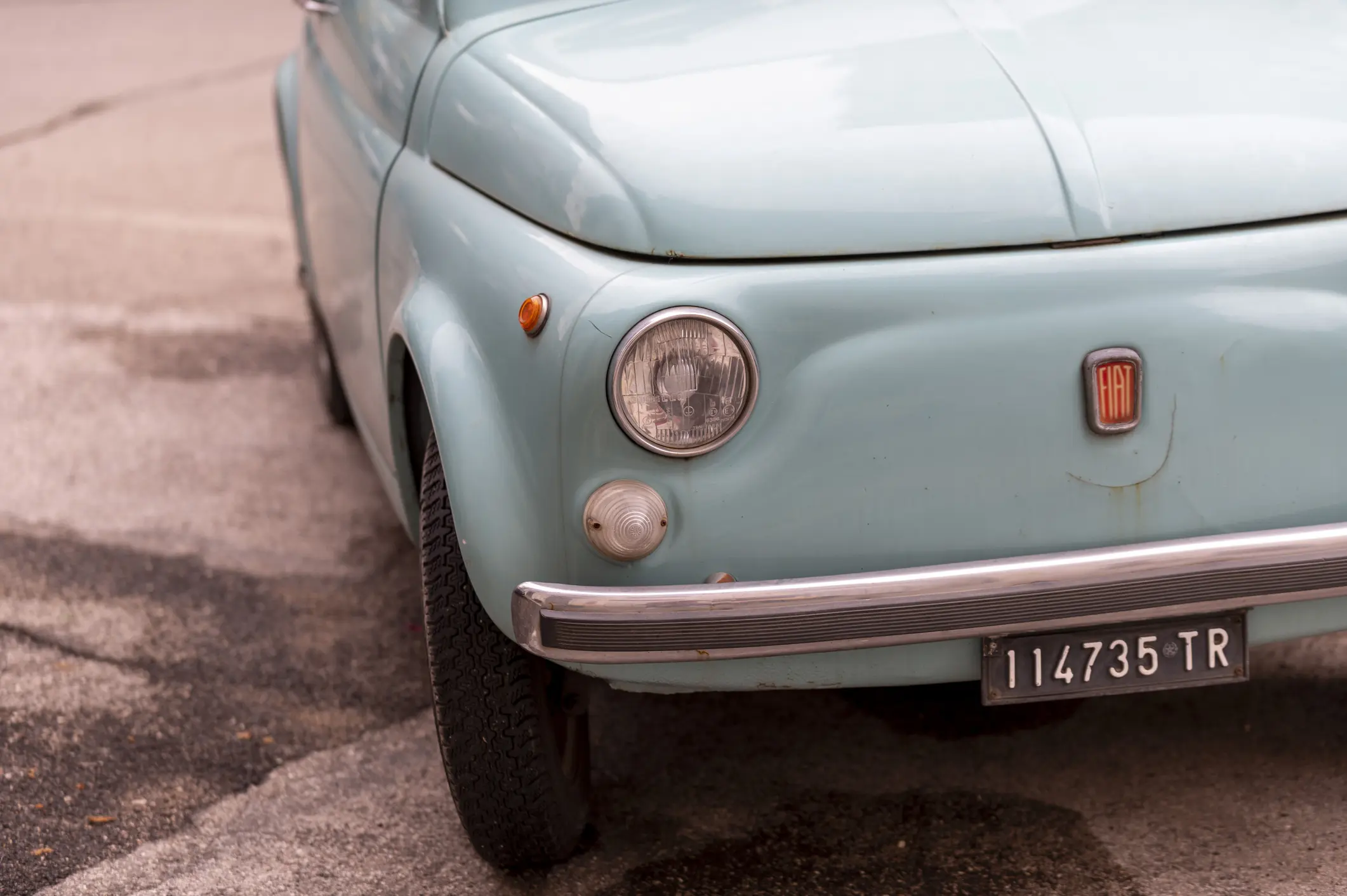 This is a close-up of a vintage light blue Fiat 500.