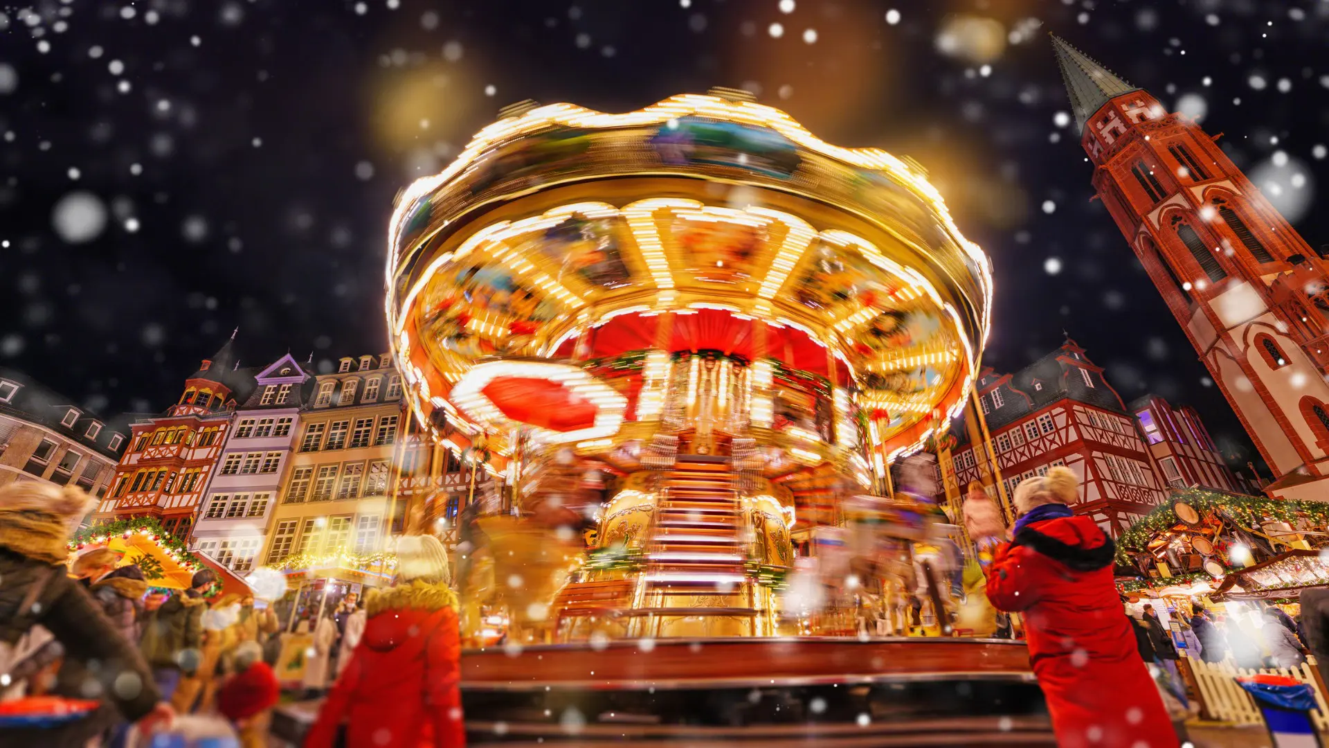 This image shows an illuminated carousel under the snow at the Christmas Market in Frankfurt. 