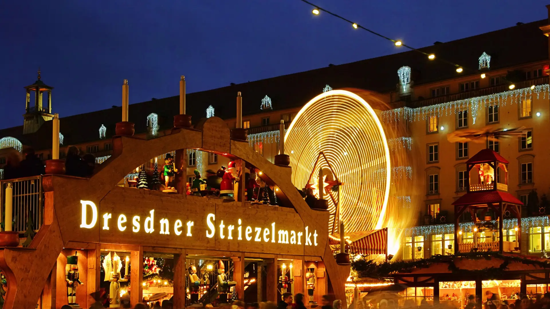This image shows an illuminated wooden sign that reads Dresdner Striezelmarkt, one of the best Christmas markets in Europe.