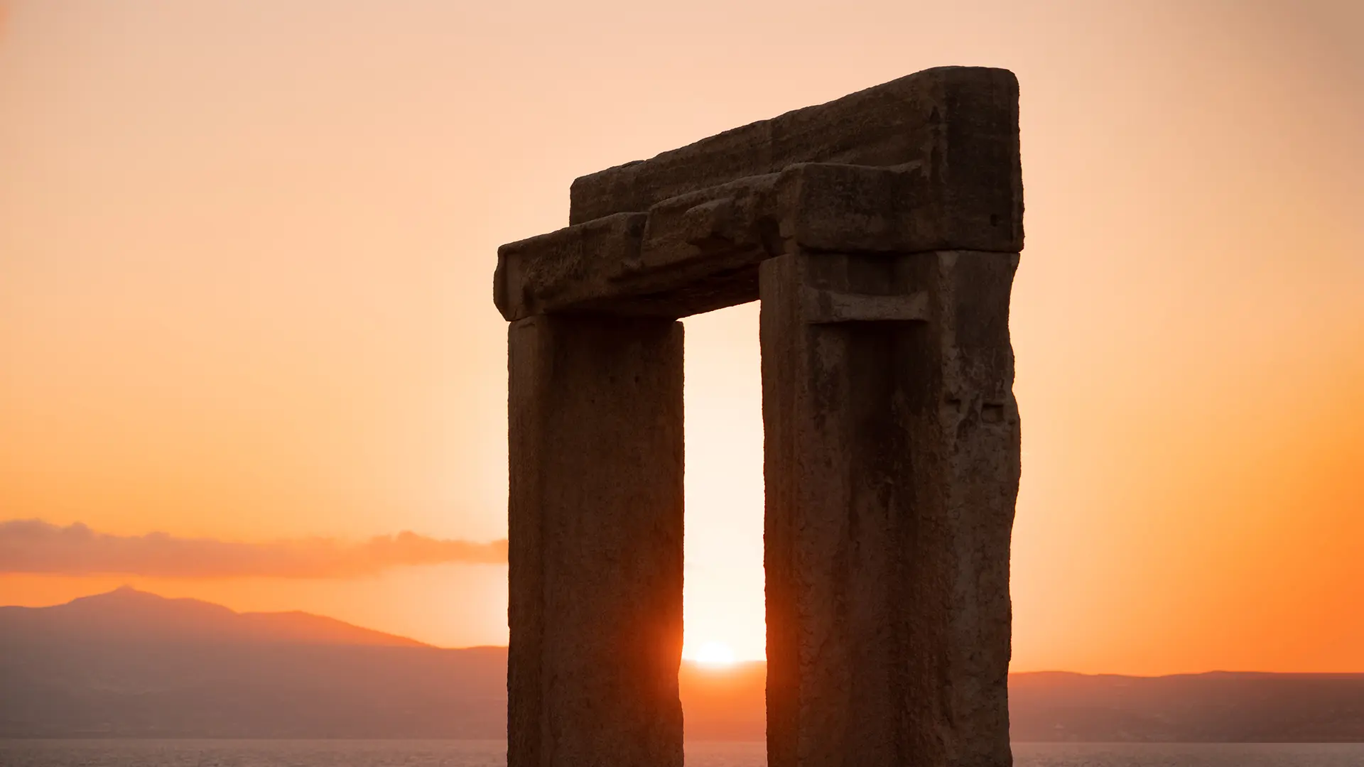 This is a close-up of Portara in Naxos. In the background, the sun is setting.