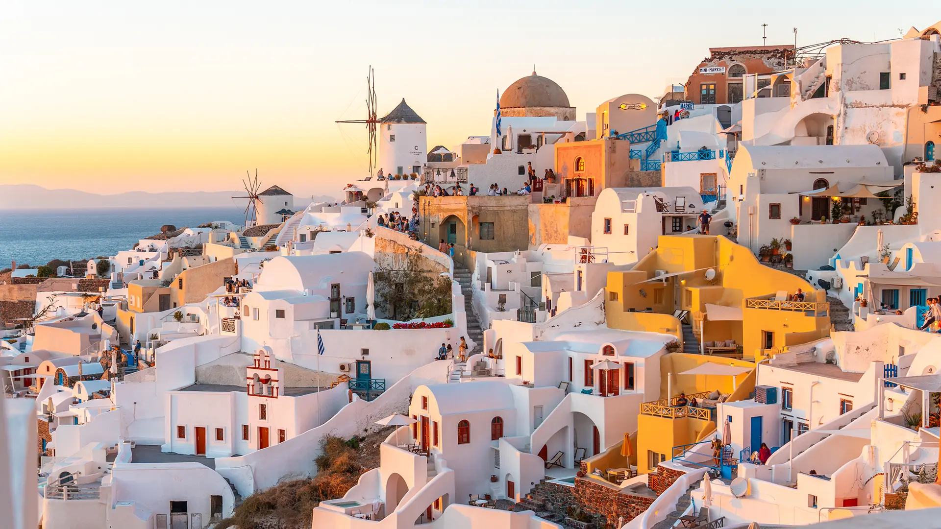 This image shows the iconic buildings of Oia at sunset. Oia boasts one of the most famous sunsets in the Cyclades.