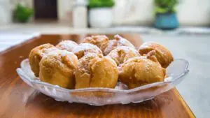 This image shows a glass bowl filled with Croatian fritule.