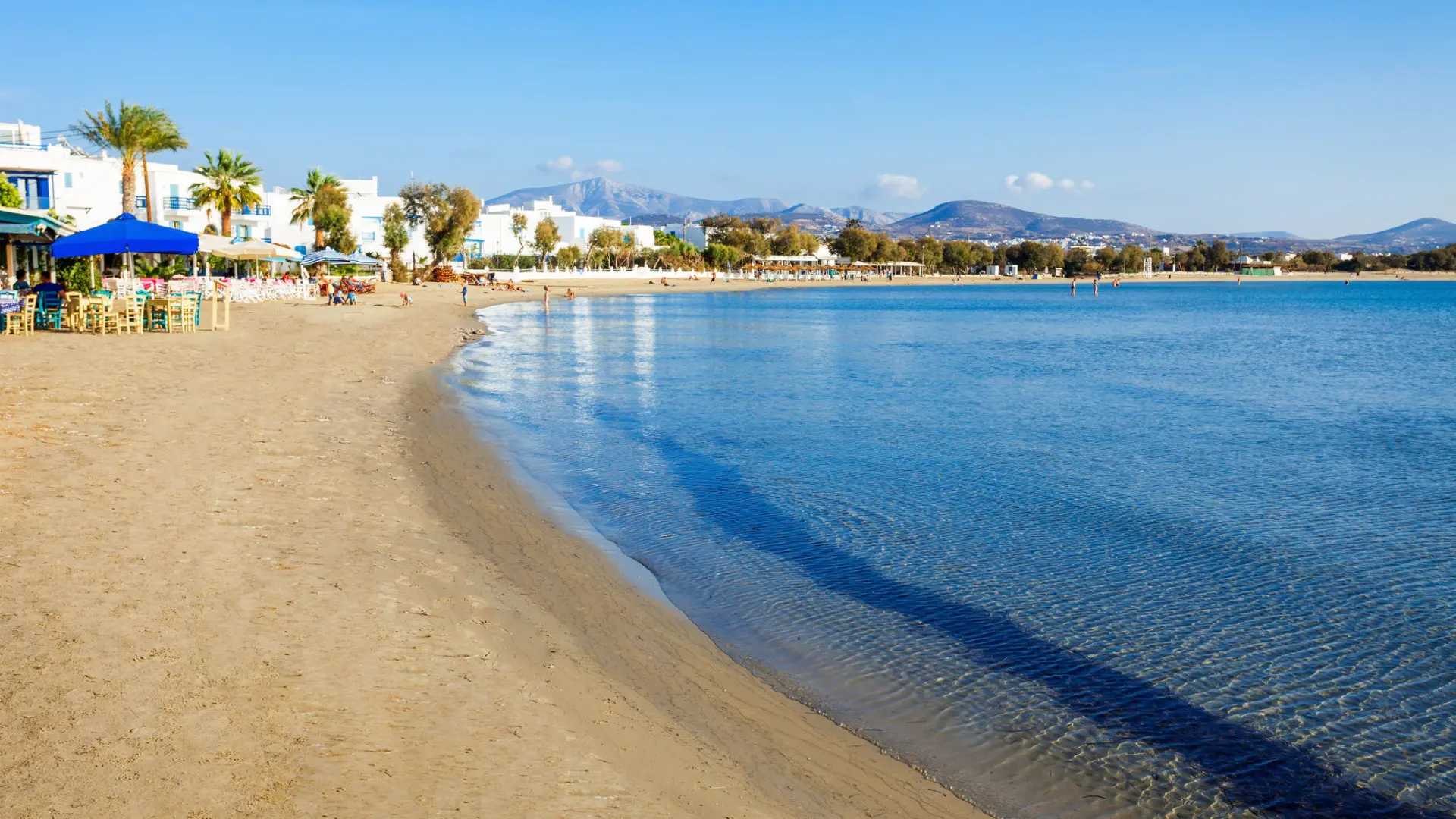 This is a panoramic view of the long sandy beach of Agios Georgios, lined with traditional restaurants right by the water.