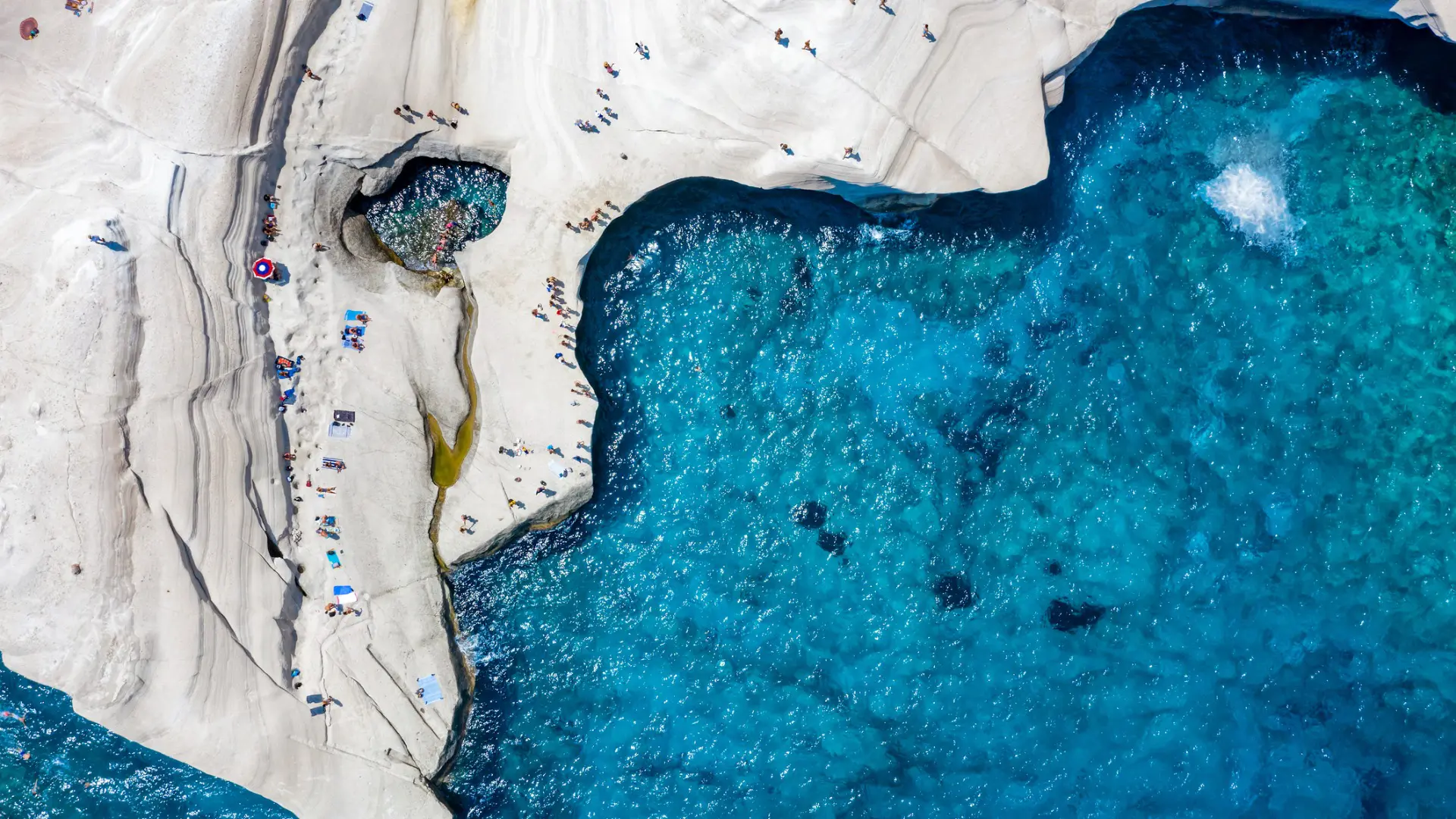 This is an aerial shot of the white rock formations and deep blue waters in Sarakiniko Milos.
