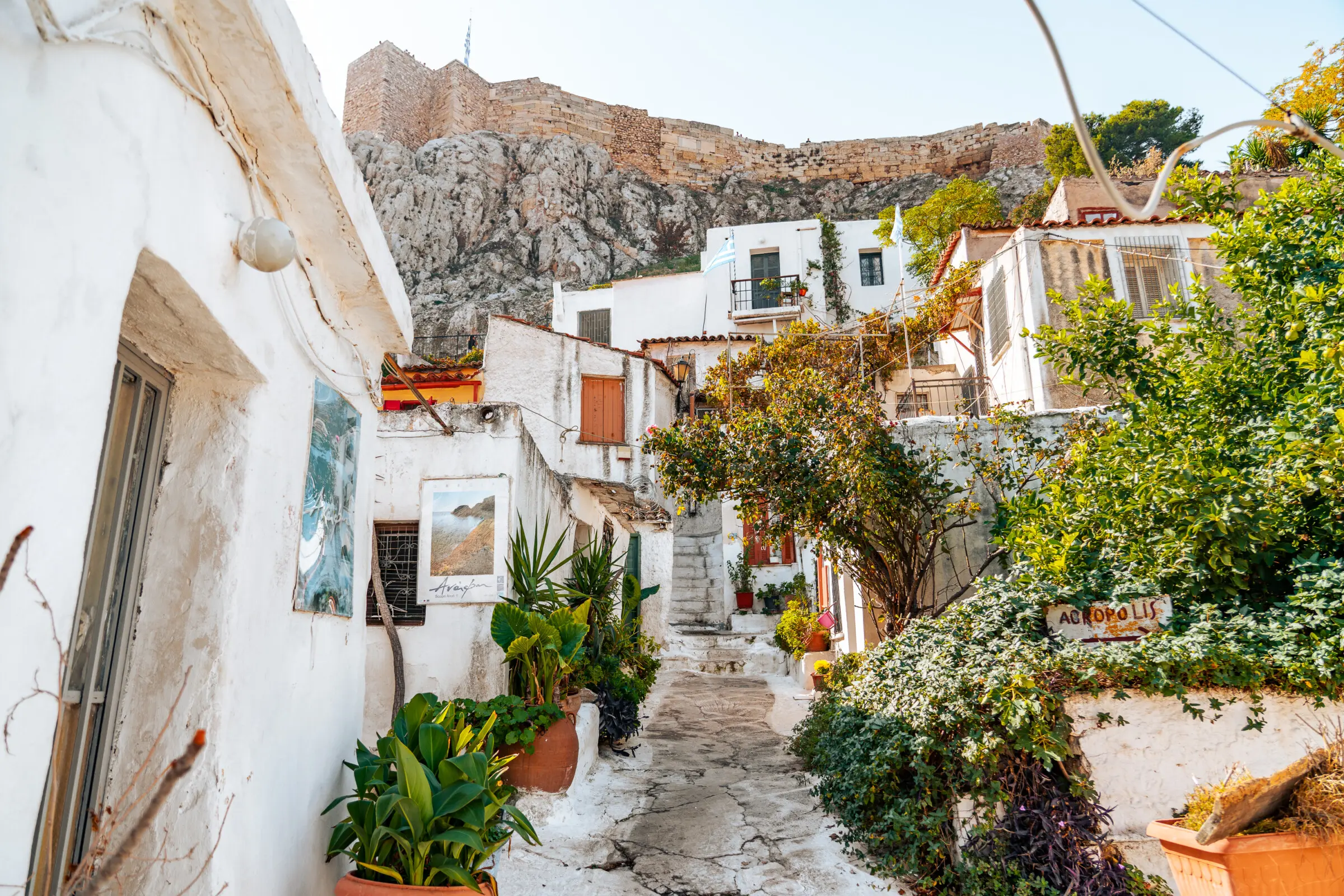This image shows a whitewashed alley in Plaka, lined with whitewashed houses. This scenic neighbourhood is right under the sacred rock of the Acropolis.