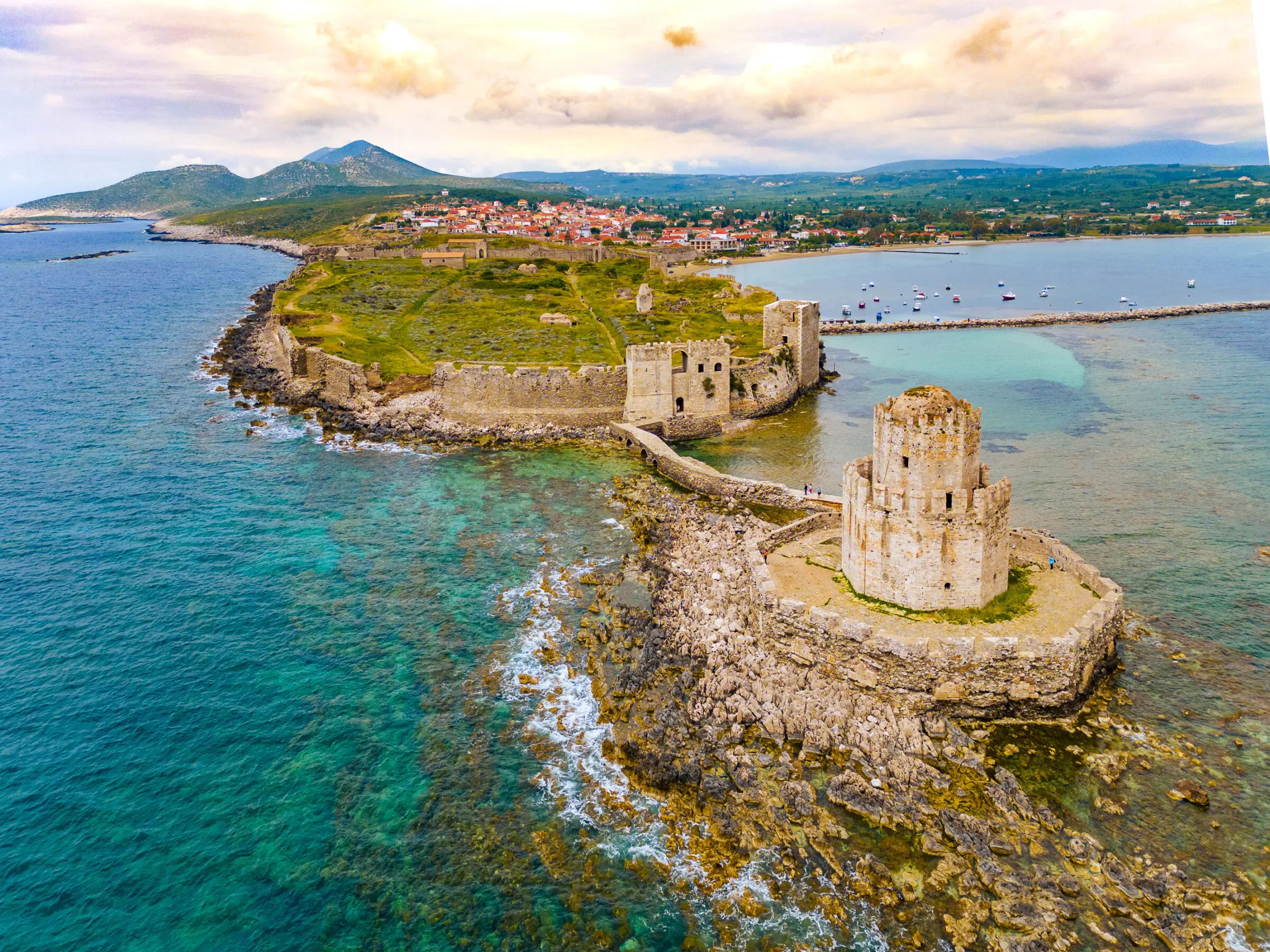 This is a drone shot of the castle of Methoni with the village of Methoni in the background.
