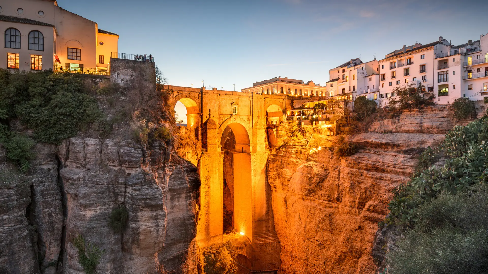 The illuminated Puente Nuevo with whitewashed buildings on either side.