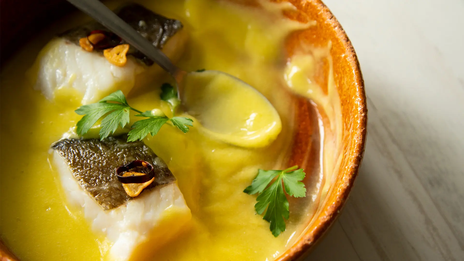 This is a close-up of Bacalao al Pil-Pil, pieces of cod doused in a thick yellow sauce.