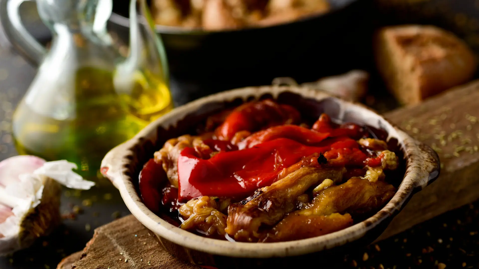 This is a close-up of Escalivada, eggplant and red bell peppers in a clay dish.