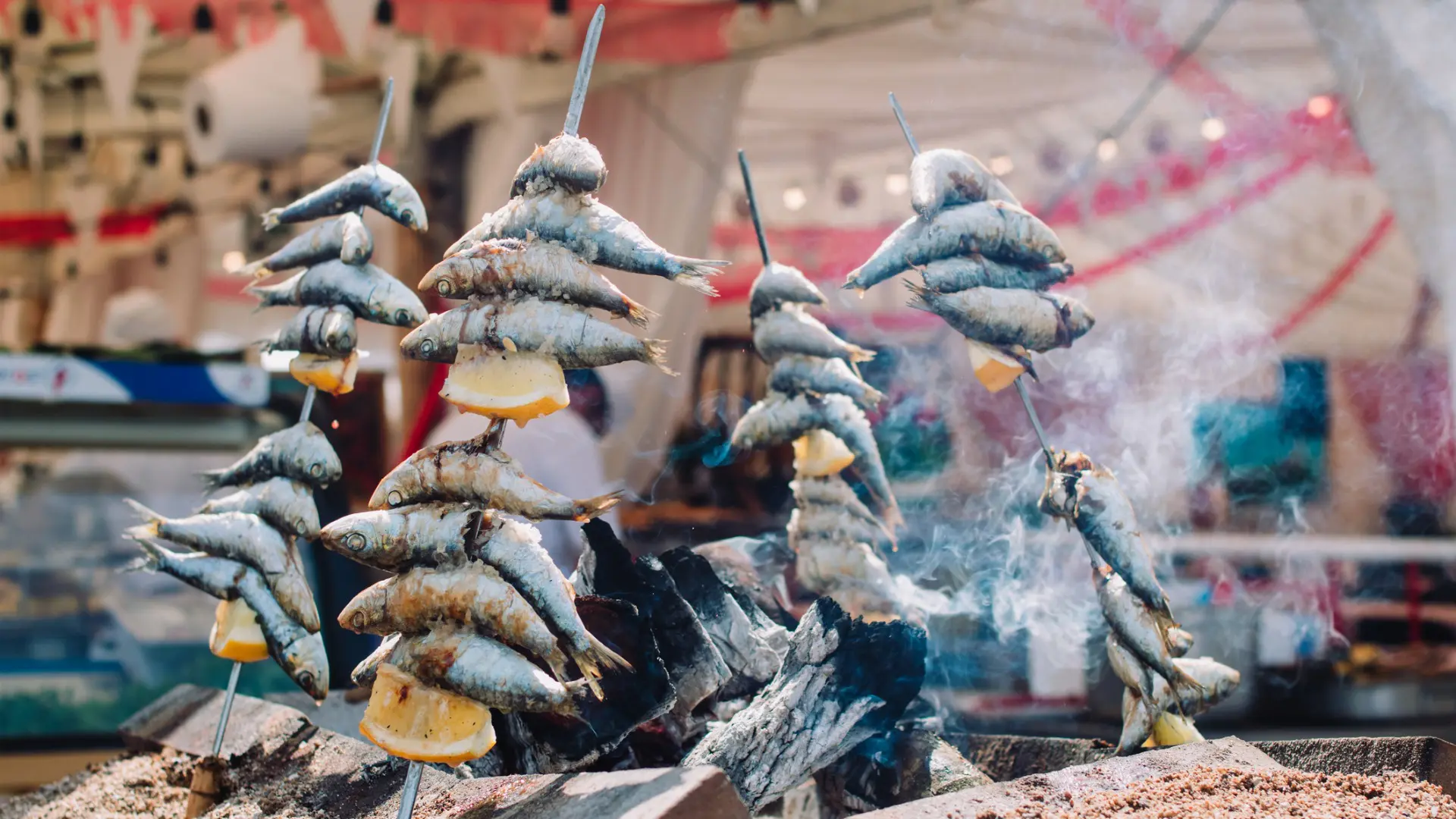 This image shows sardines on sticks grilled over fire.