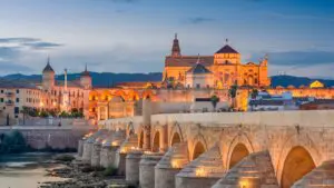 The illuminated Roman Bridge of Cordoba at dusk.