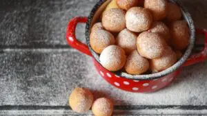 This is a top-down shot of a red pot with white dots filled with fritule.