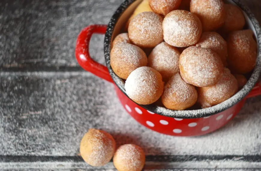 This is a top-down shot of a red pot with white dots filled with fritule.