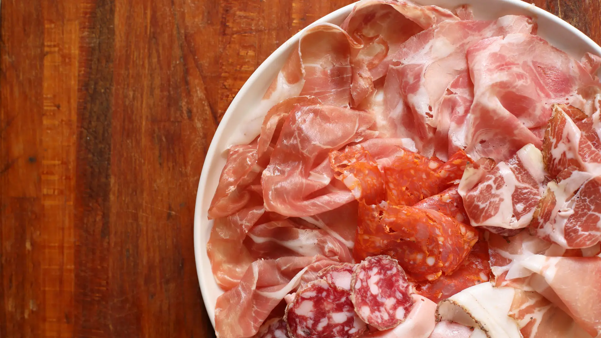 This is a plate filled with Italian cold cuts, like salami, prosciutto etc.