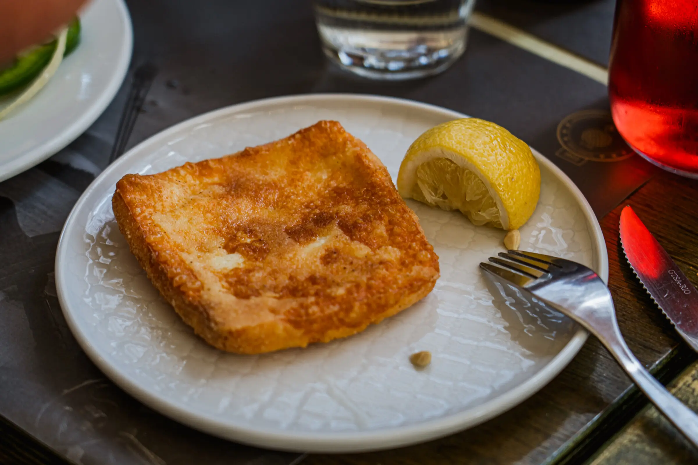 A close up of a plate with Saganaki Cheese on it.