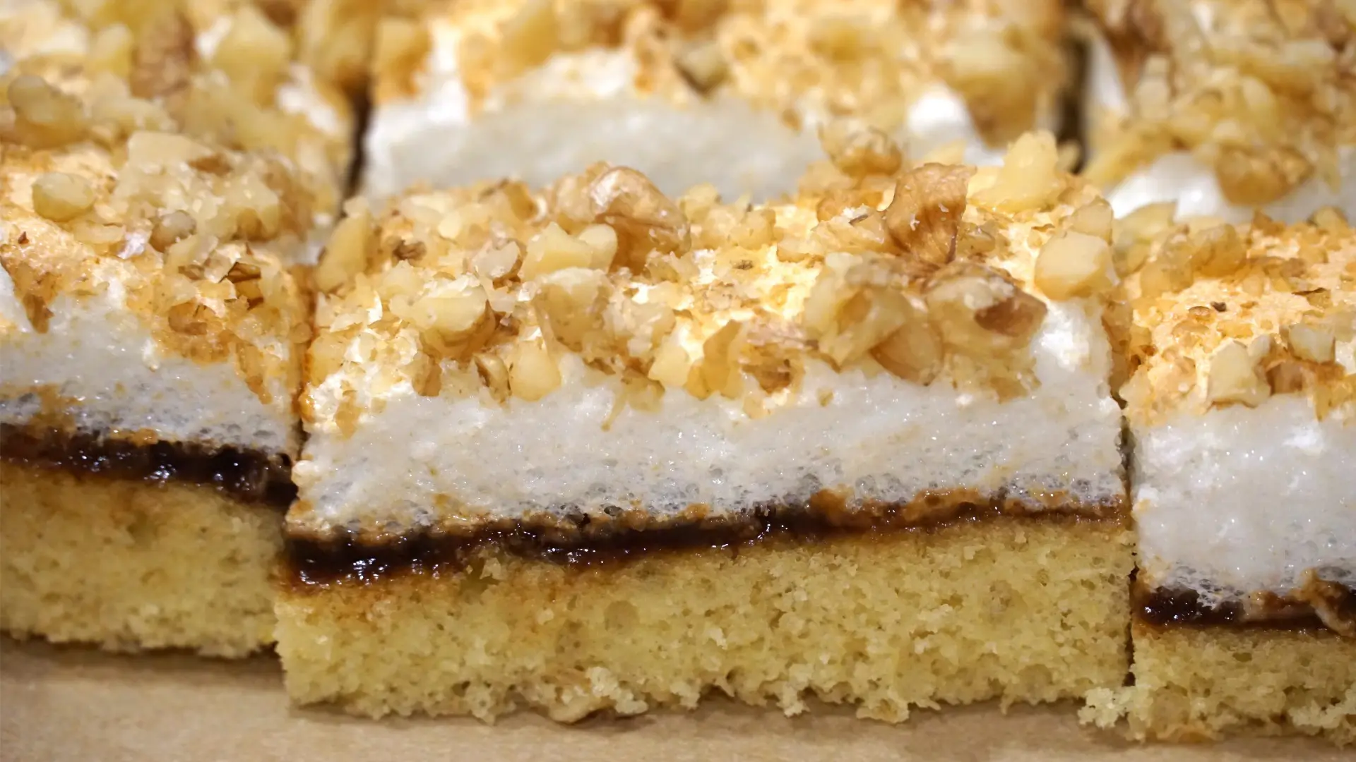 A close up of pieces of layered cake topped with chopped walnuts.