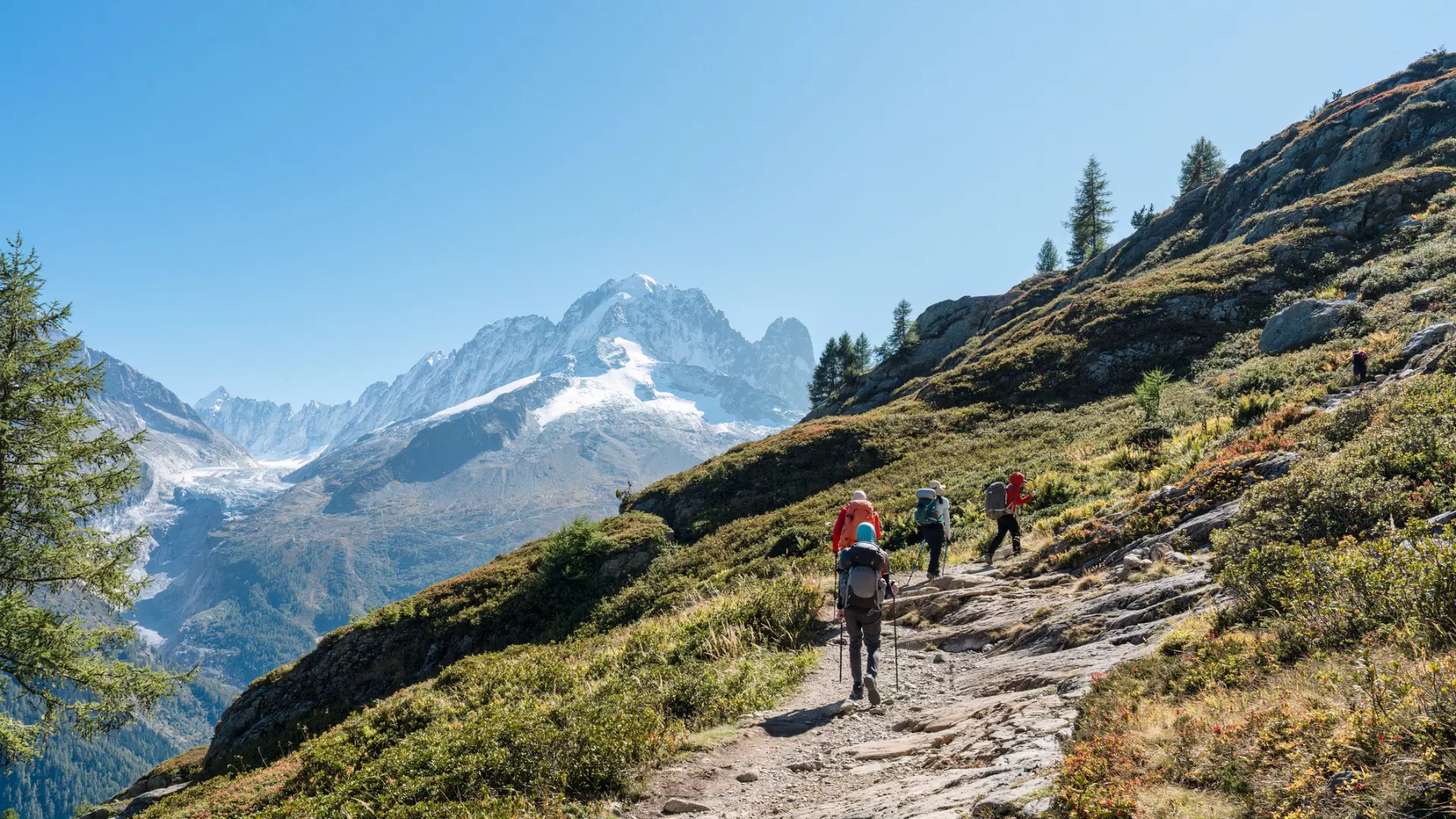 A group of hikers hiking on a summit trail to Lac Blanc amidst the French Alps on a sunny day. If you're into hiking, summer is the best time to visit France.