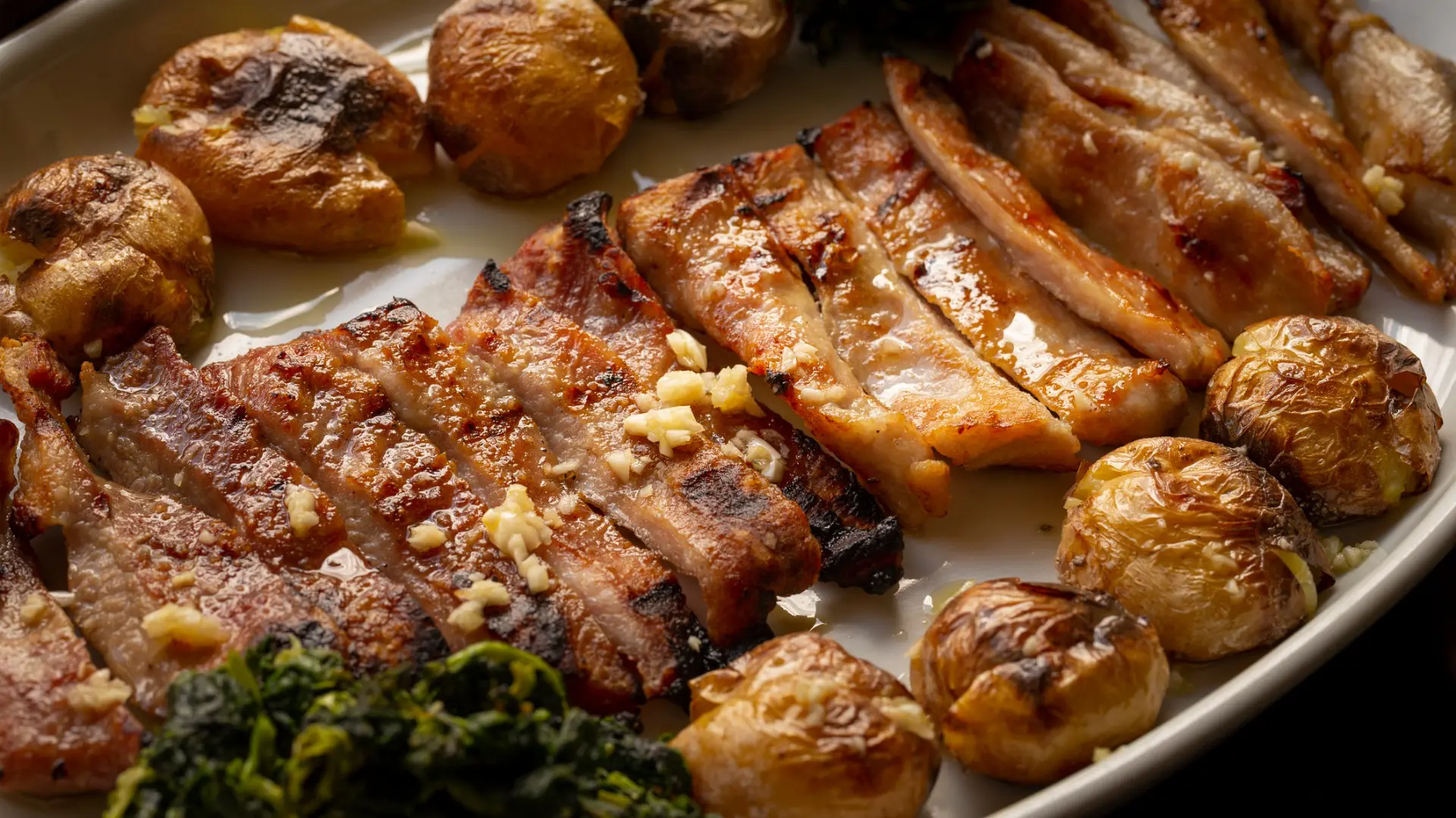 A close up of a dish with sliced Porco Preto and baby potatoes.