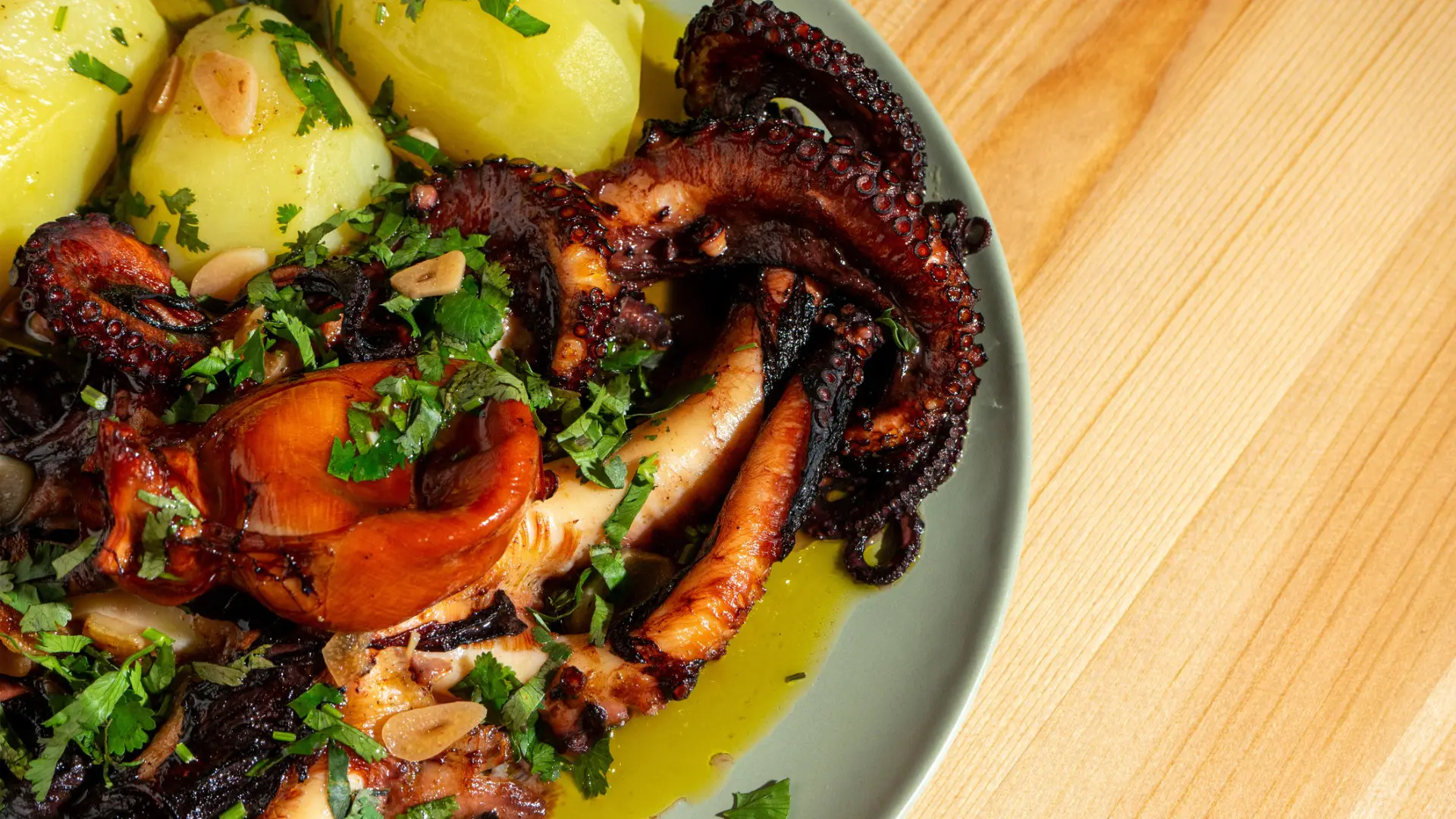 A close up of a dish with grilled octopus and boiled potatoes.