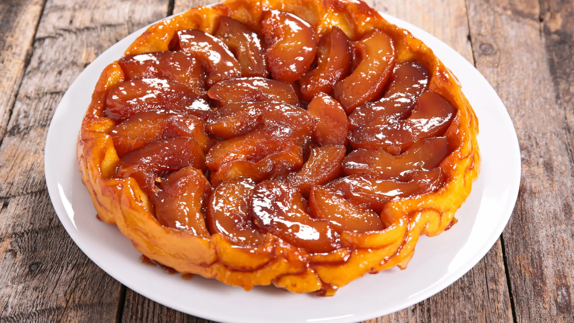 A close up of a Tarte Tatin topped with caramelized apple slices.