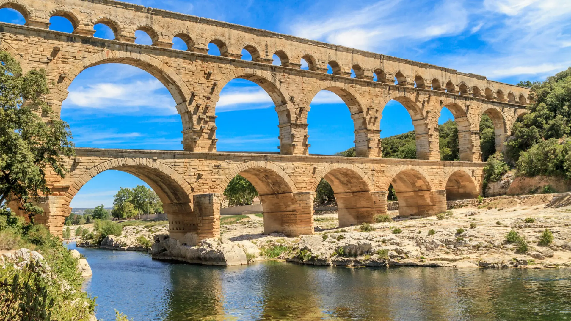 A Roman Aqueduct over a river under a clear blue sky.