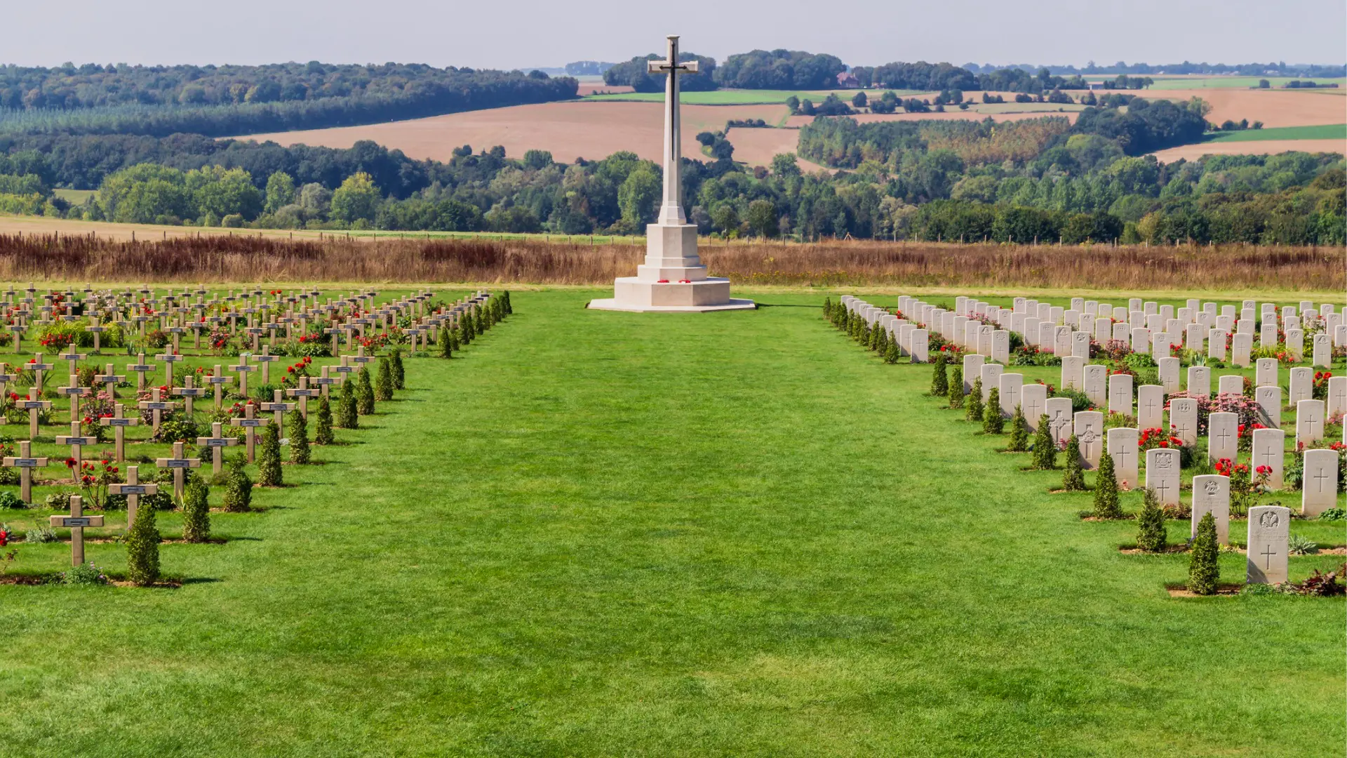 A large cross flanked by tombstones in a green field. The Thiepval Memorial is part of one of the collective UNESCO World Heritage Sites in France.