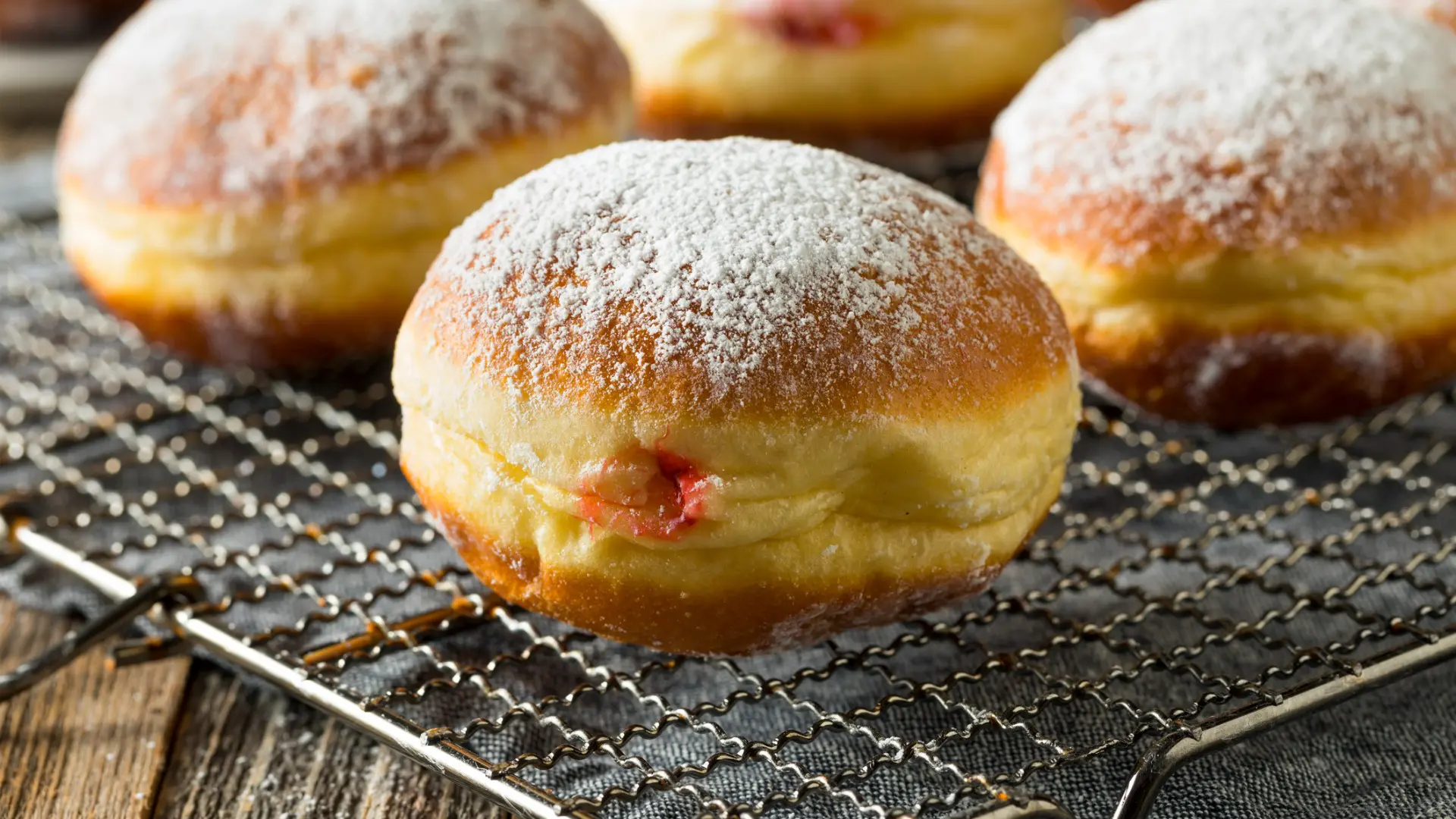 A close up of three doughnuts filled with jam and topped with icing sugar.