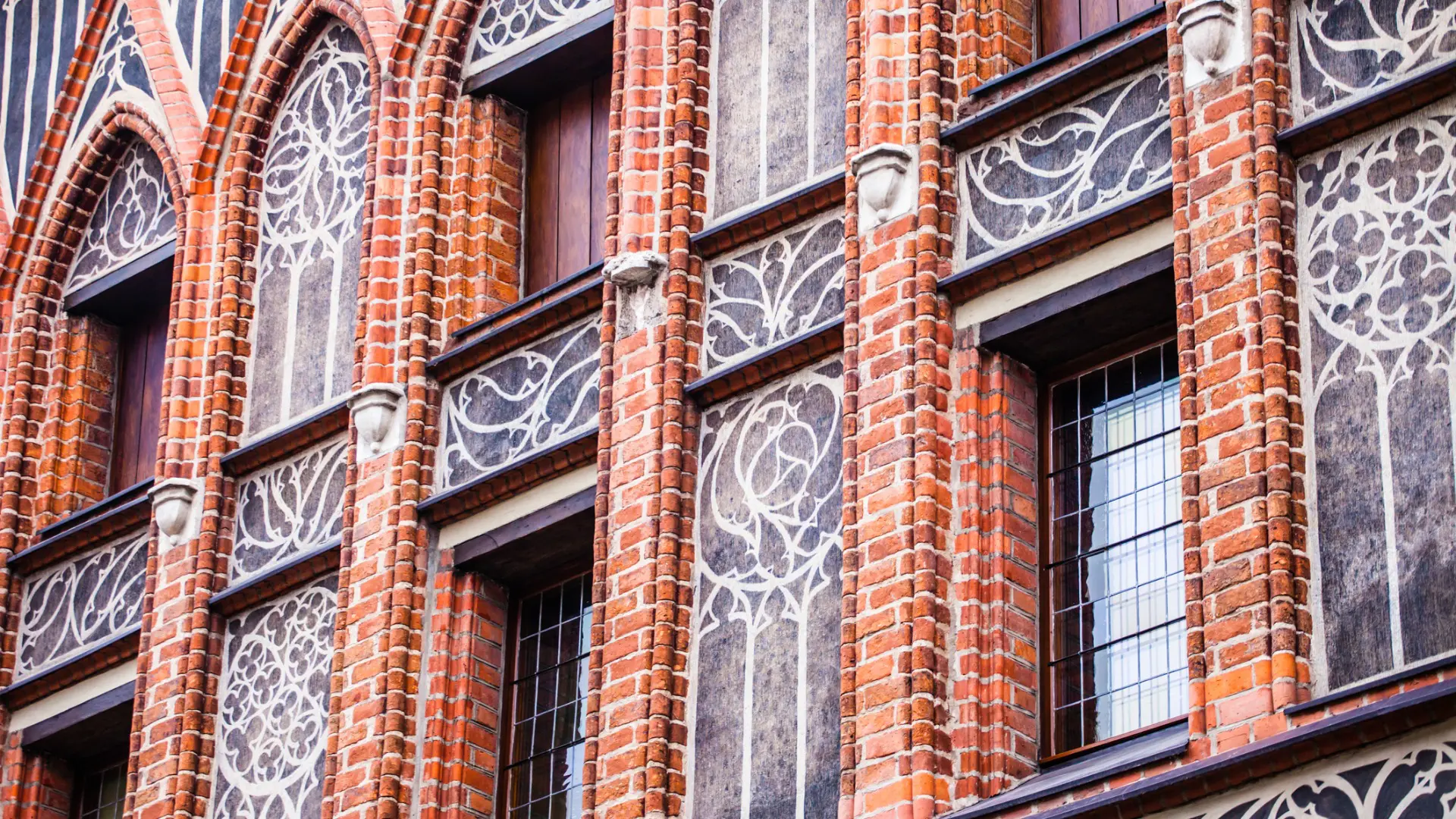 A close-up of the facade of Copernicus House. There are columns of red bricks on each side of every window.