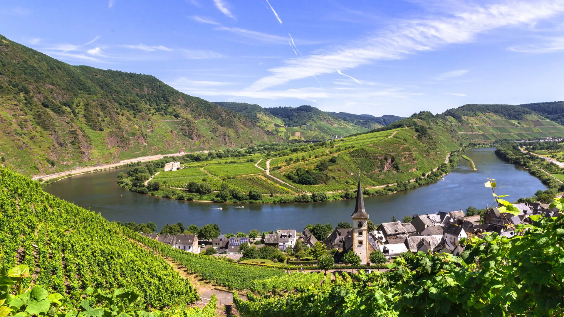 Panoramic view of a lush valley, a river, and a small traditional town.