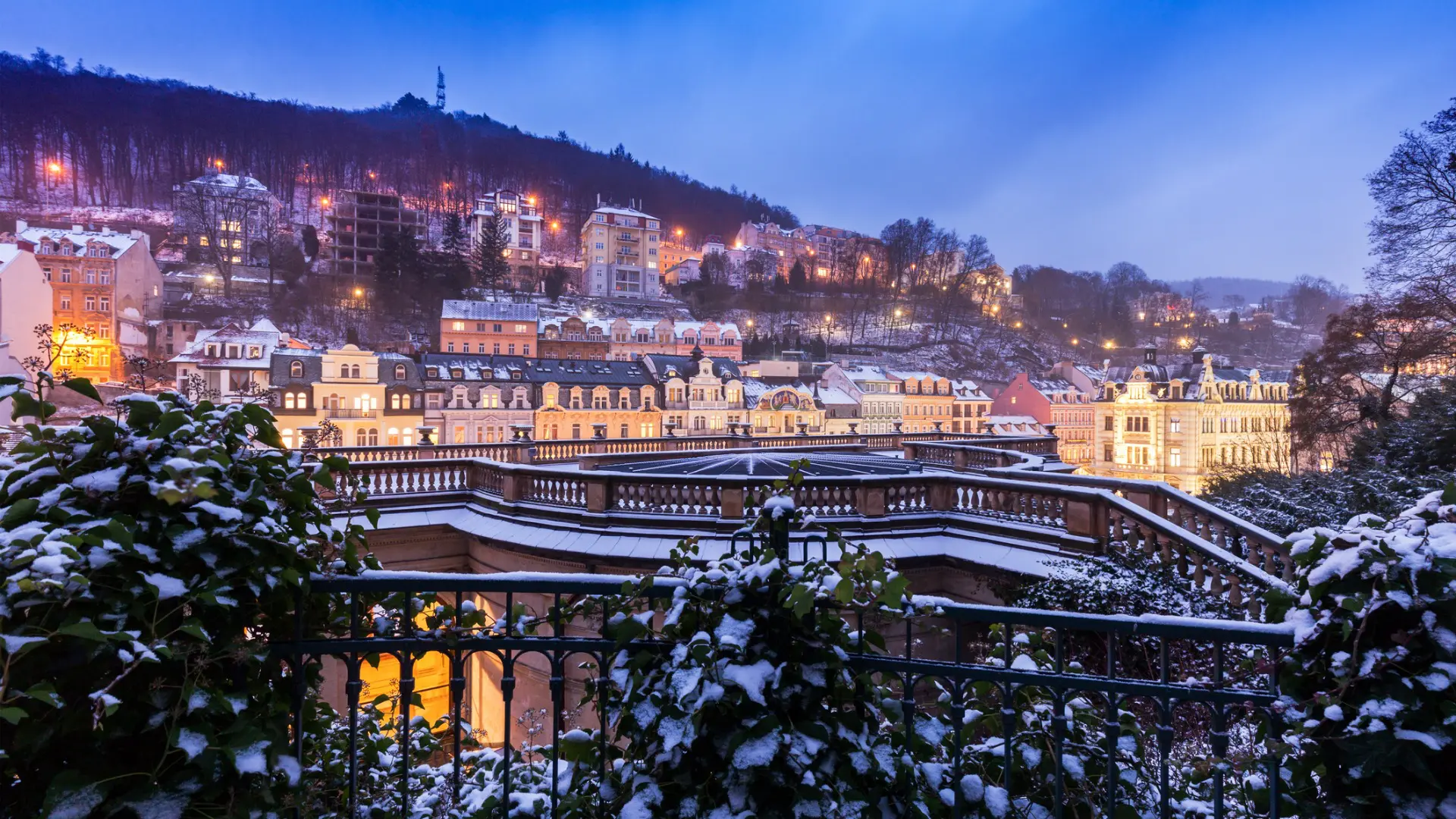 A panoramic view of a snowy Karlovy Vary at dusk. The spa town is one of the best places to go if you're wondering where to travel in 2025 in Europe.