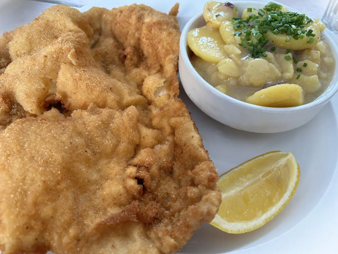 Wiener schnitzel and potato salad on a plate, with a lemon wedge