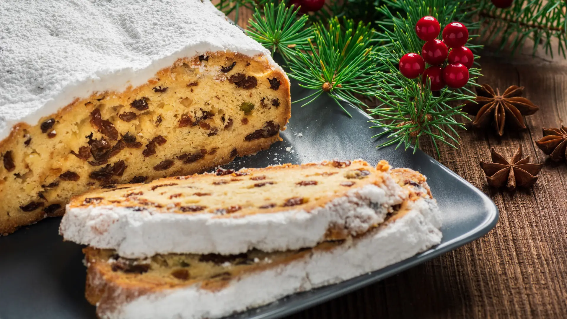 A cake filled with raisins and nuts, topped with icing sugar.