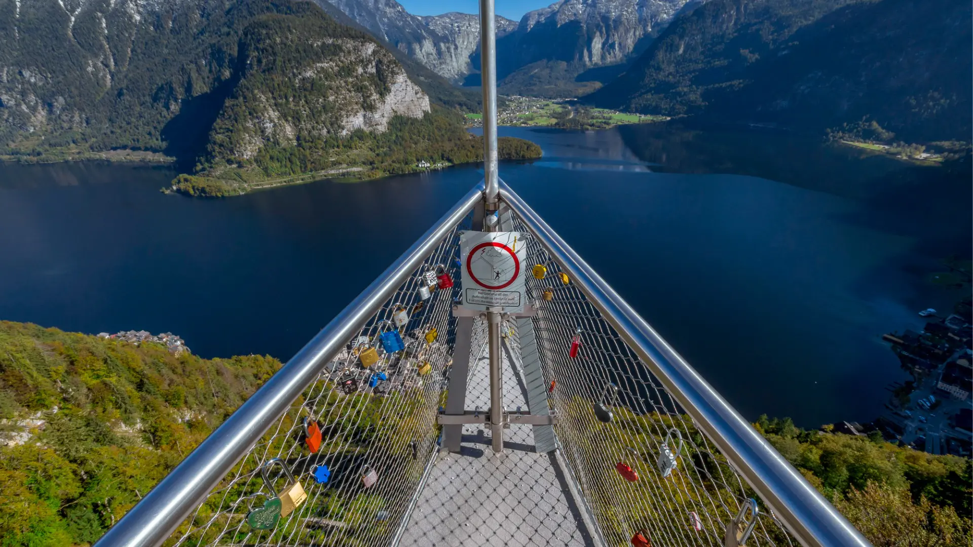A skywalk with love padlocks and views over a lake.