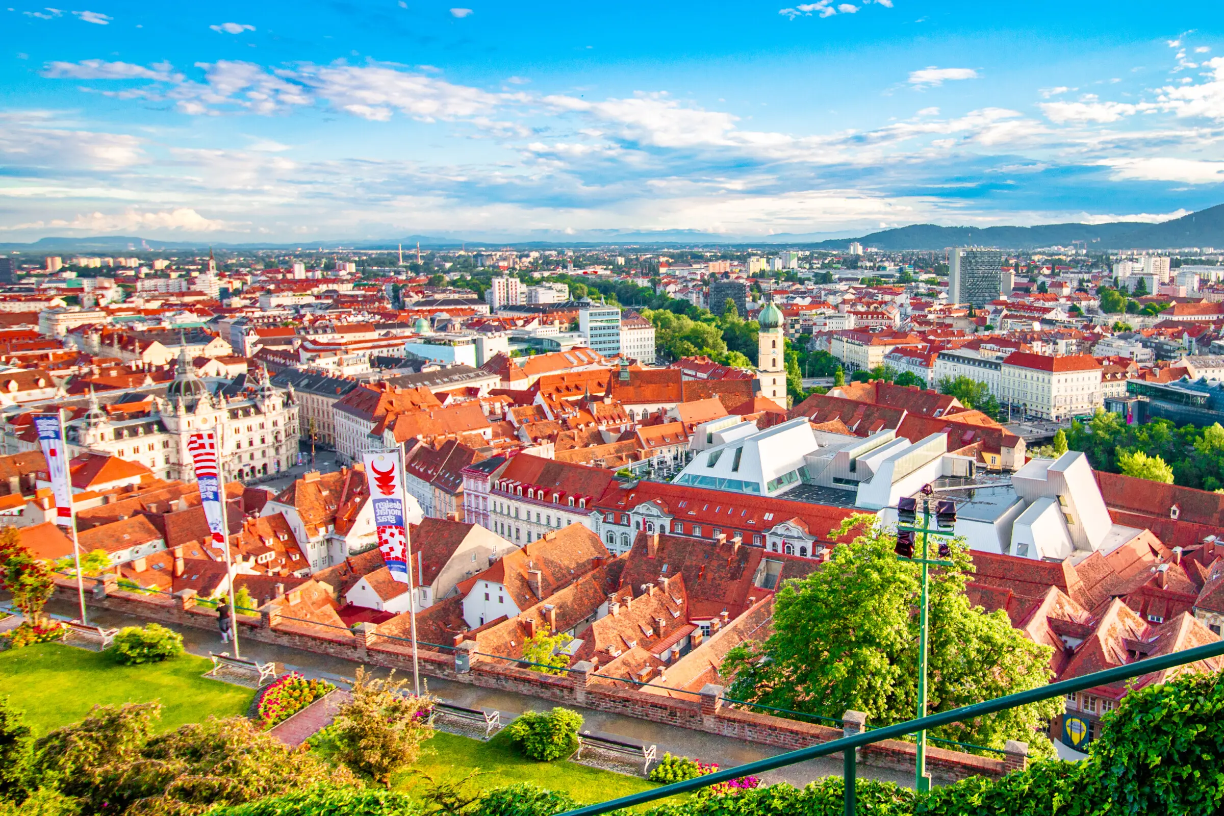 A panoramic view of Graz's red rooftops with a few modern buildings in the background.