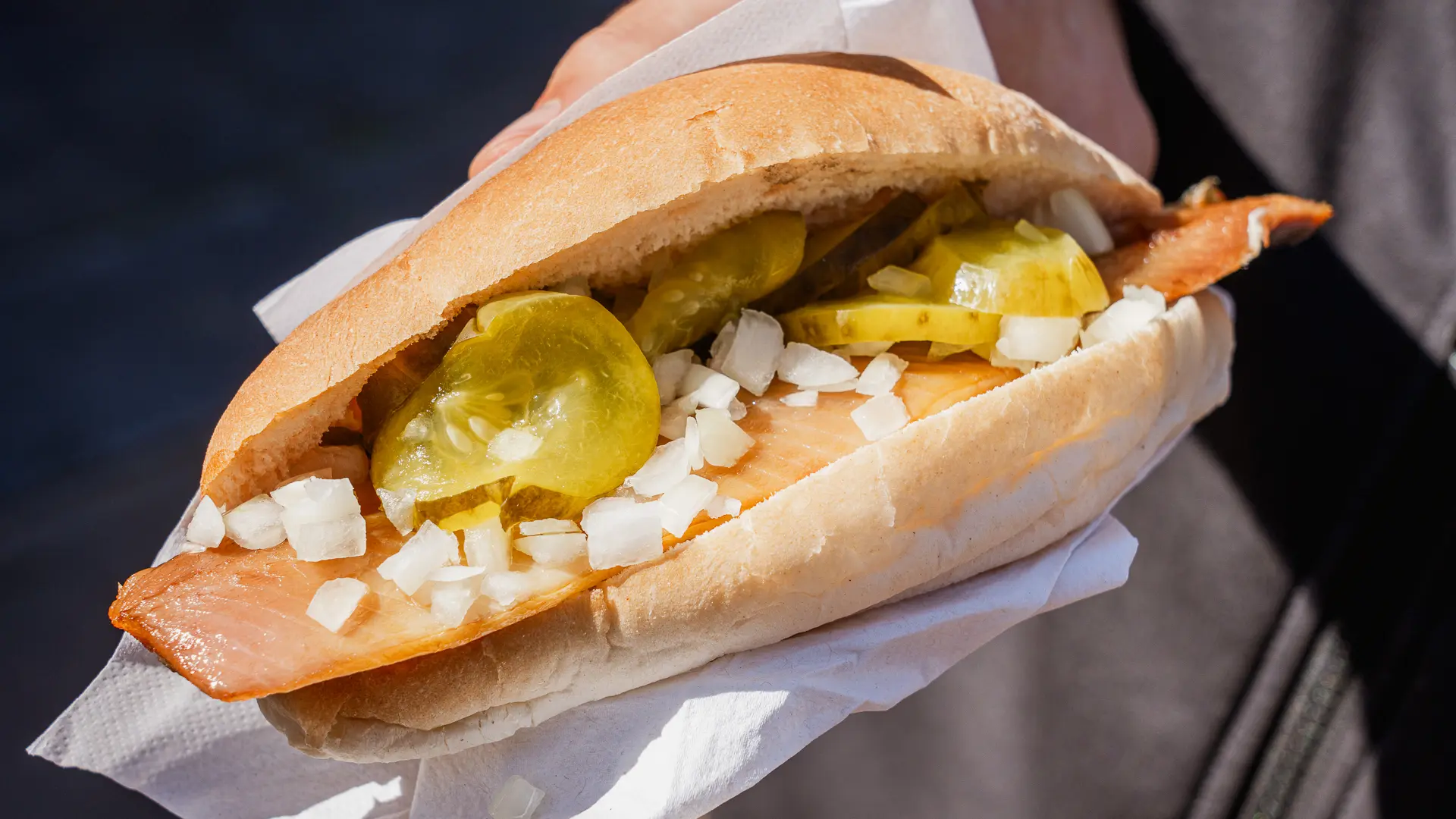 Dutch fish sandwich with soused herring, gherkins and chopped raw onions, one of the most typical foods to try in Amsterdam.