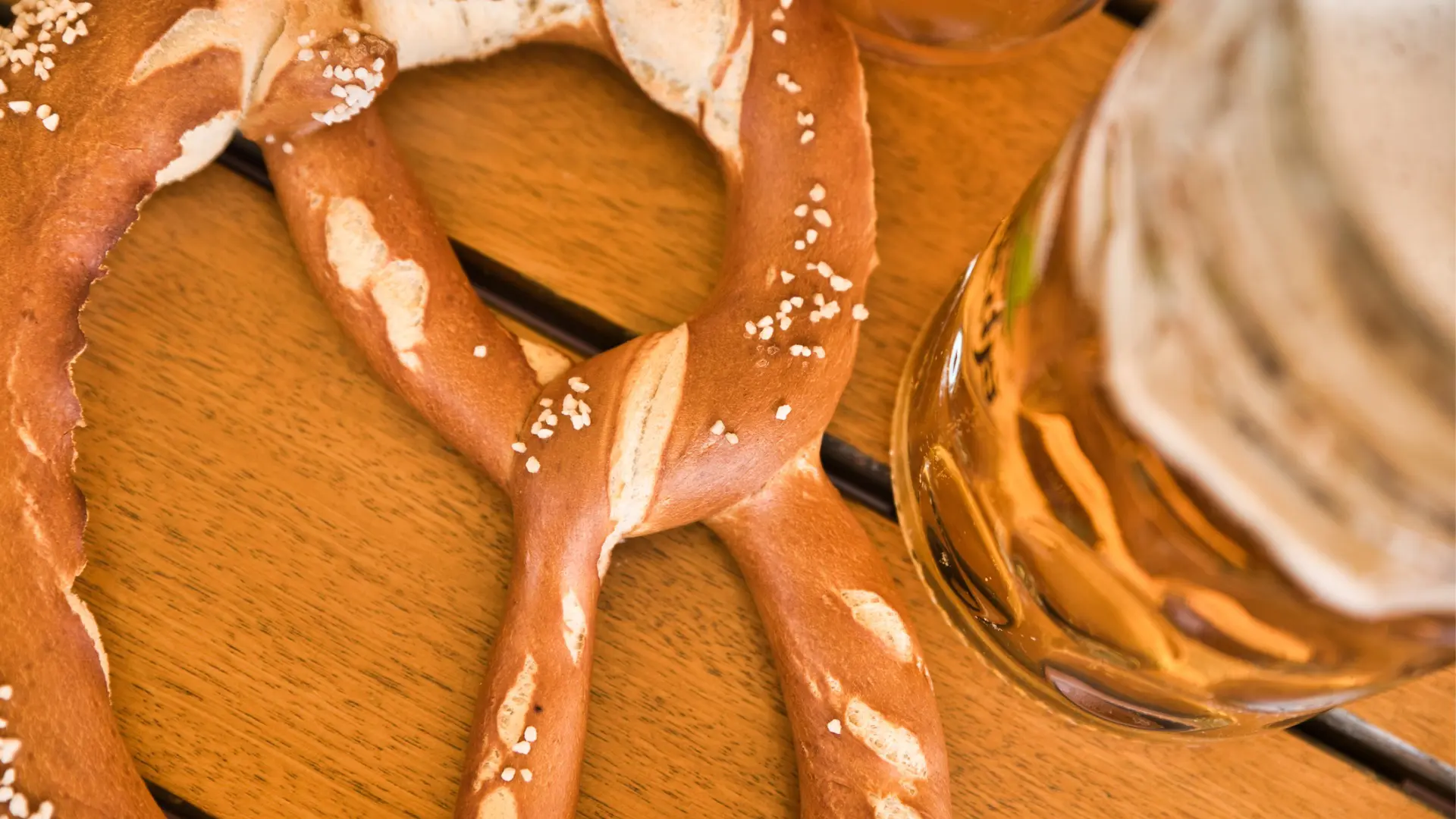 A close up of a pretzel and a glass of beer.