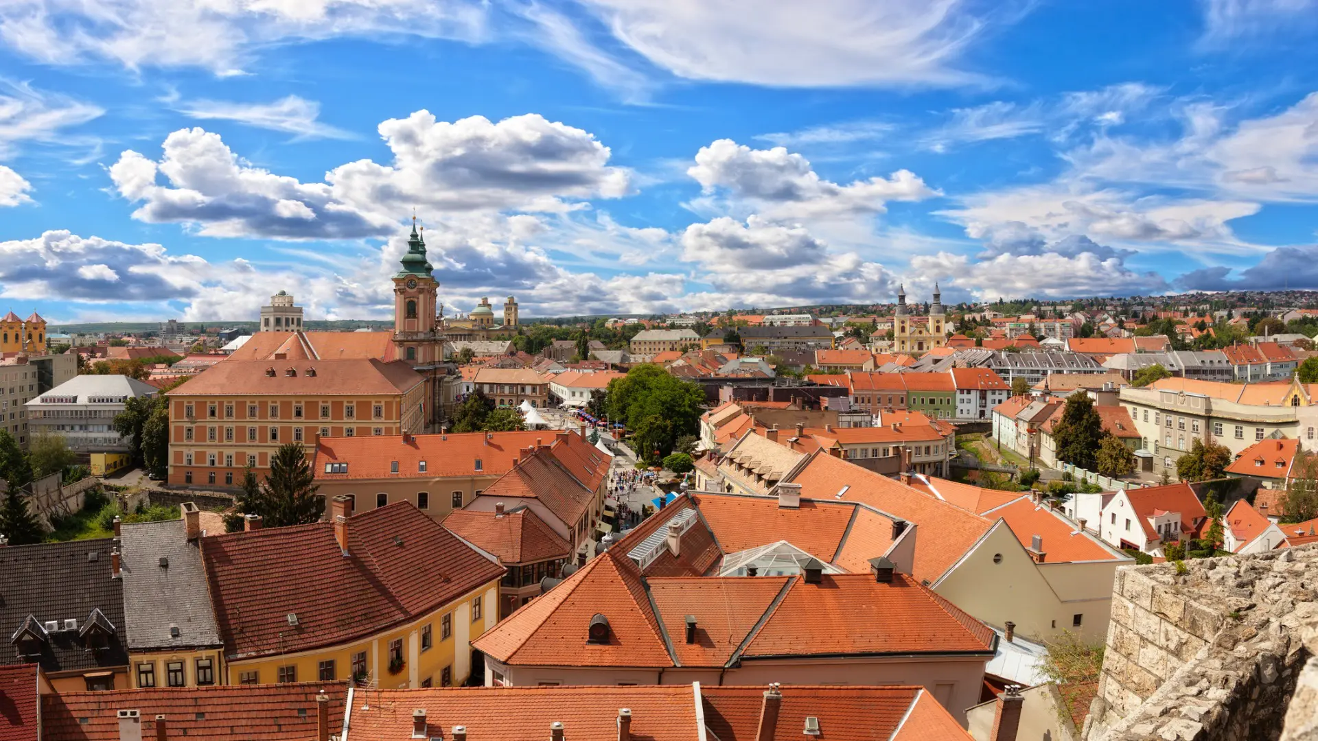 A panoramic view of a town with red rooftops under a blue sky.