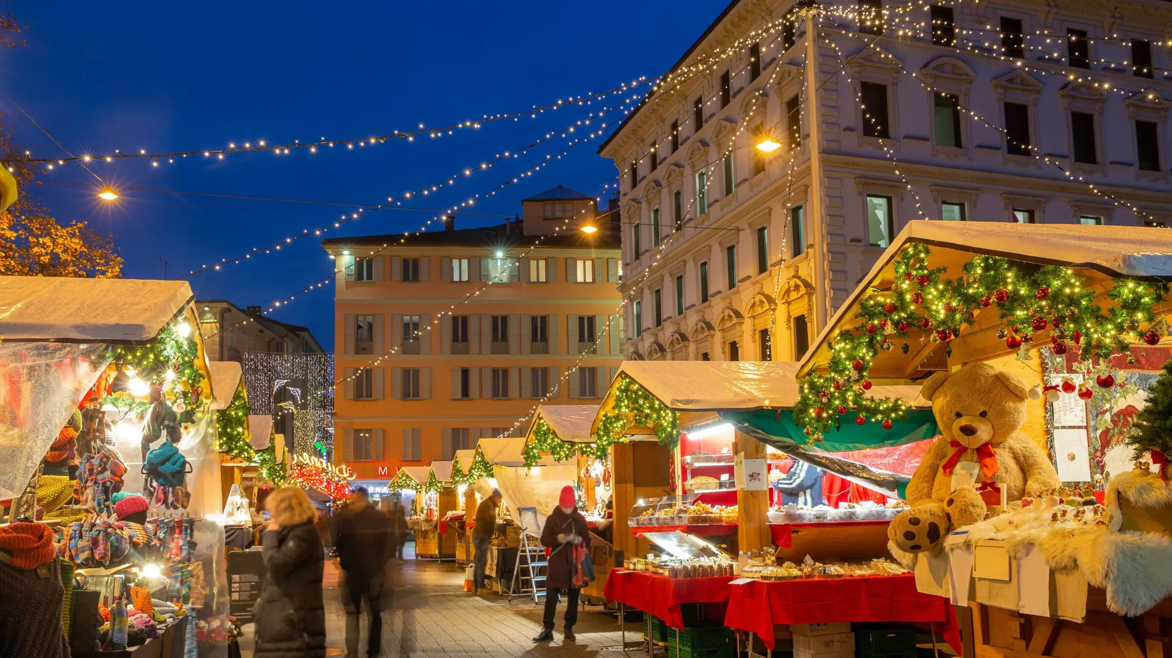 A city lit up for Christmas and stalls selling souvenirs and treats.