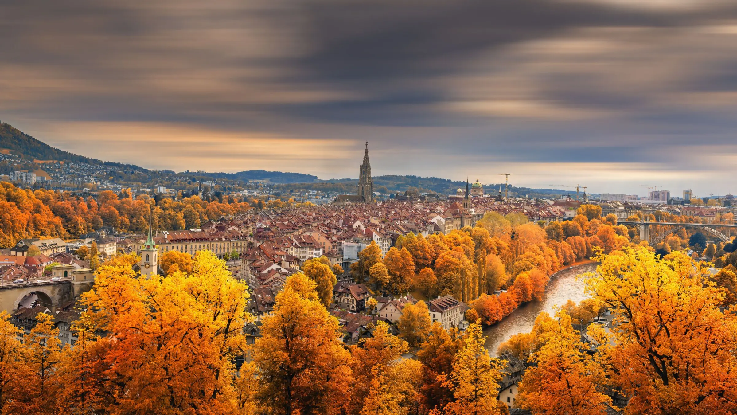 A panoramic view of Bern. Red-tiled buildings and fall foliage. For many, fall is the best time to visit Switzerland.