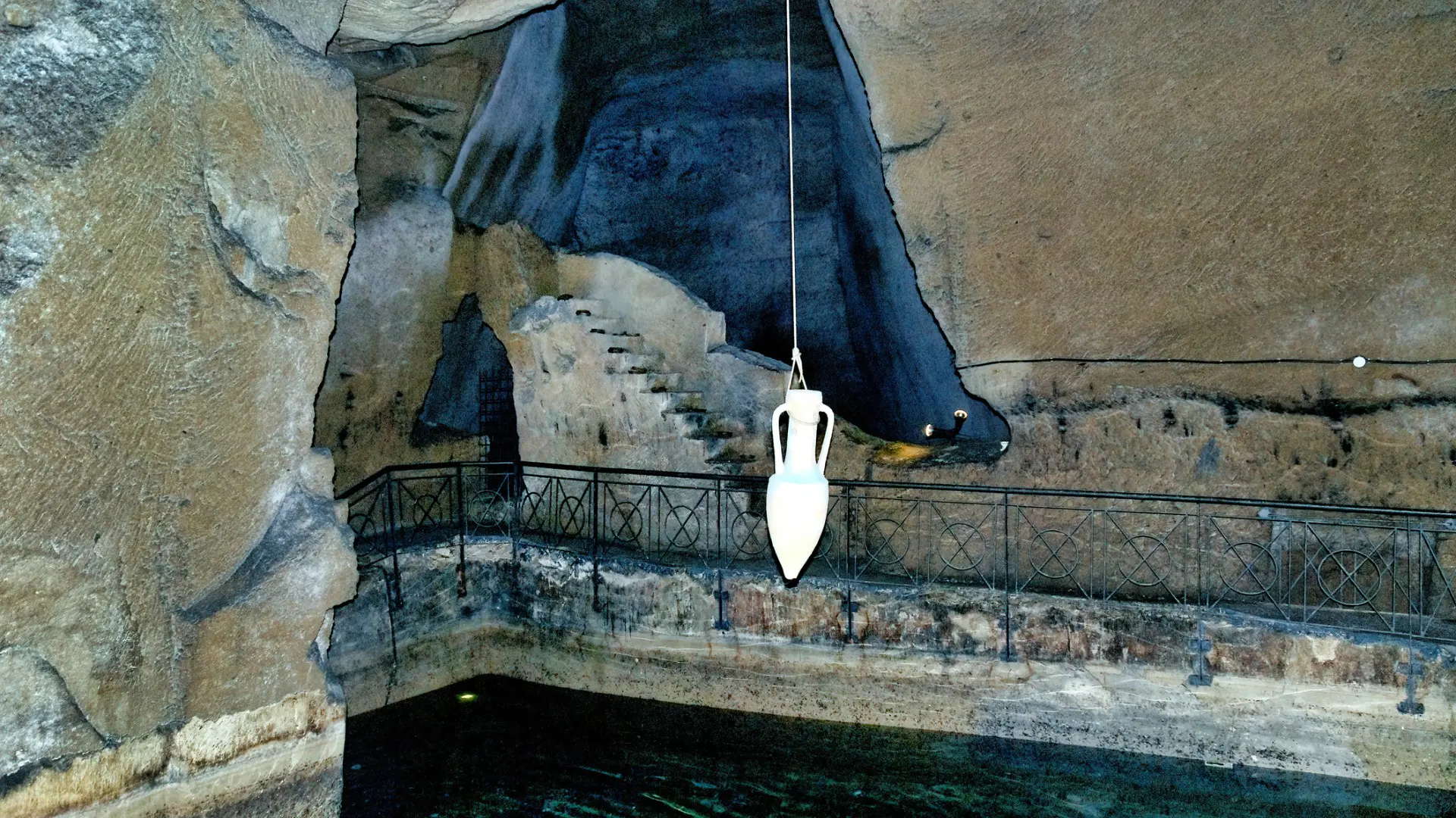 An amphora hanging from a rope in an underground chamber.