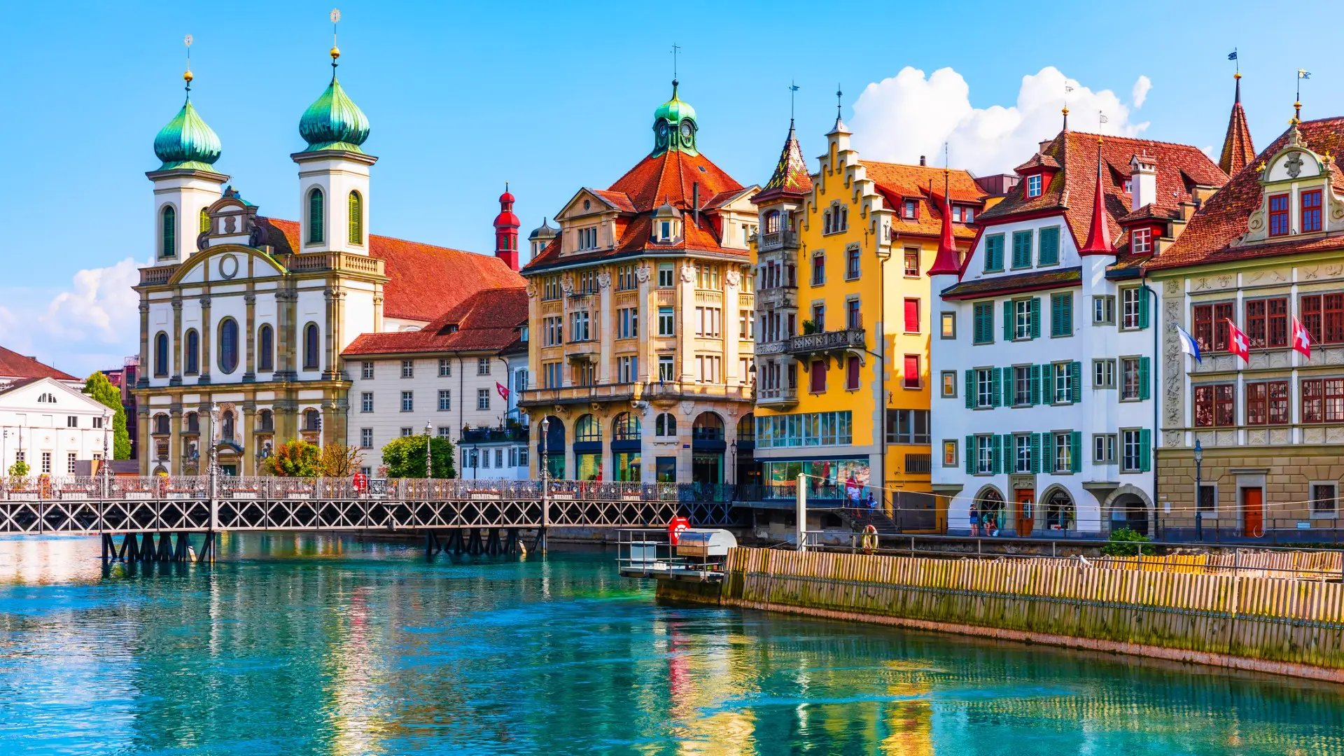 A row of gorgeous buildings along the tranquil waters of a lake in Lucerne, one of the best places to visit in Switzerland.