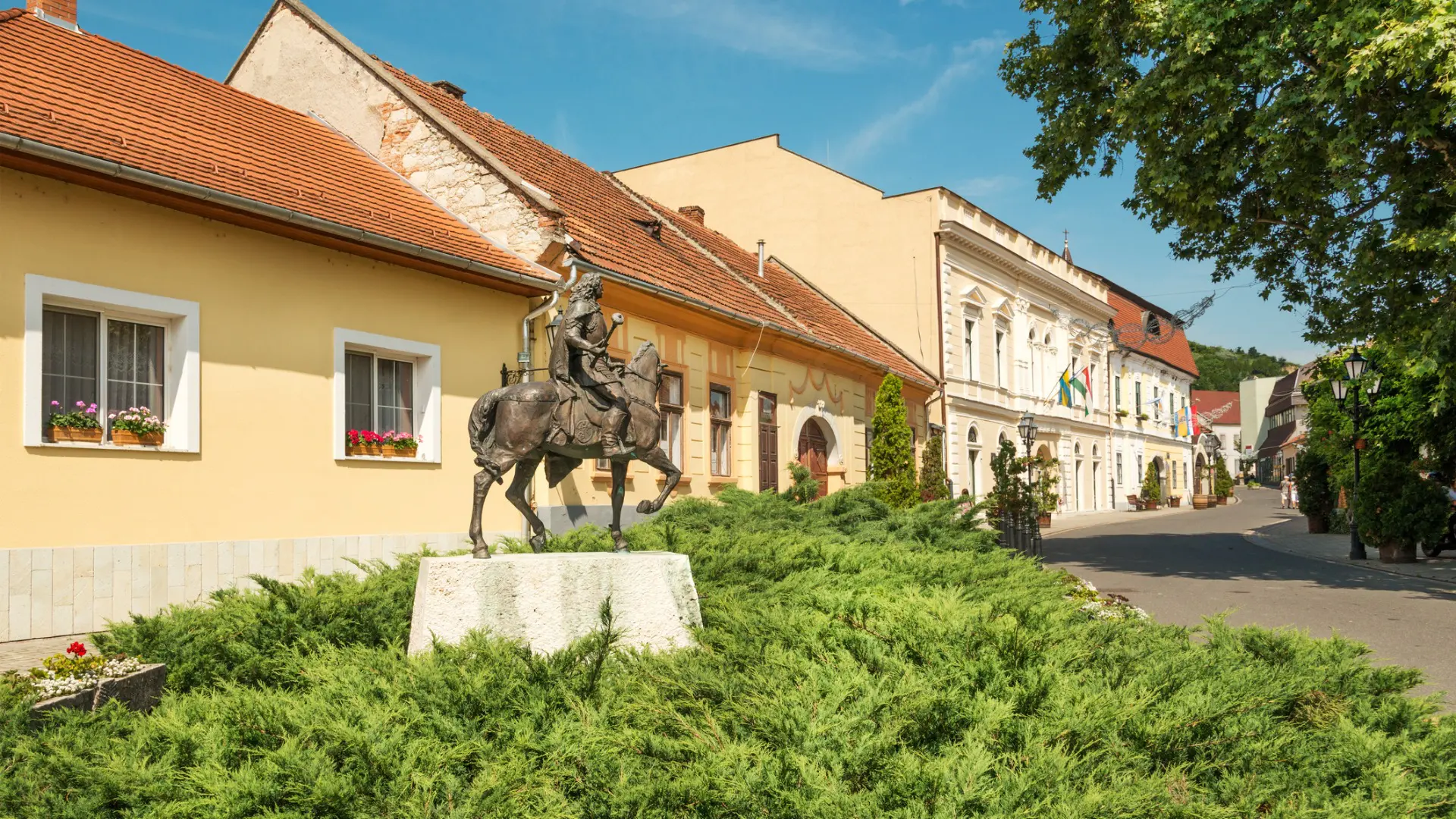 A statue of a man riding a horse in front of a row of beautiful buildings in the town of Tokaj, one of the best places to visit in Hungary.