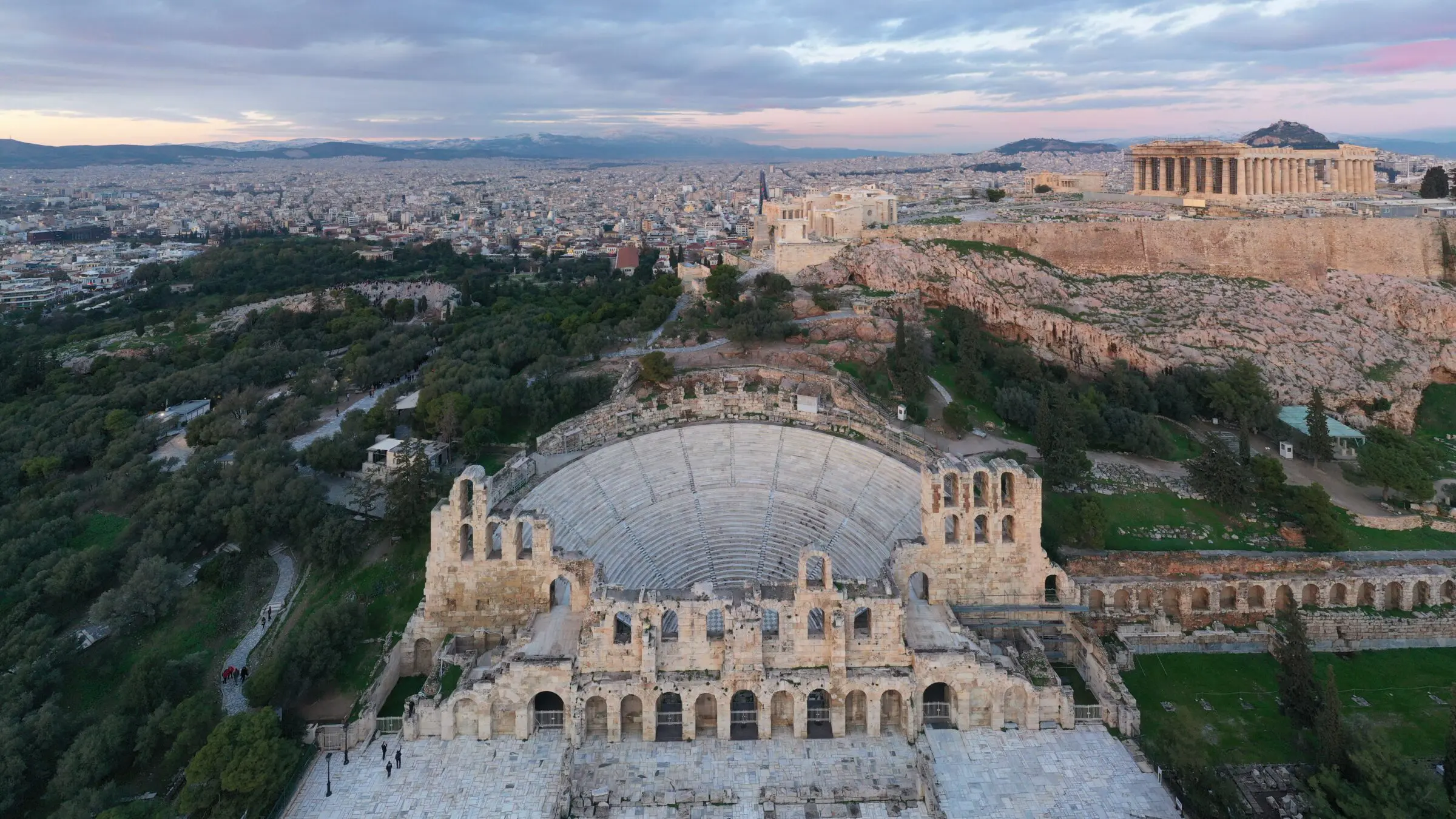 A panoramic view of the Odeon of Herodes Atticus with the Acropolis, Lycabettus Hill, and the modern city of Athens in the background.
