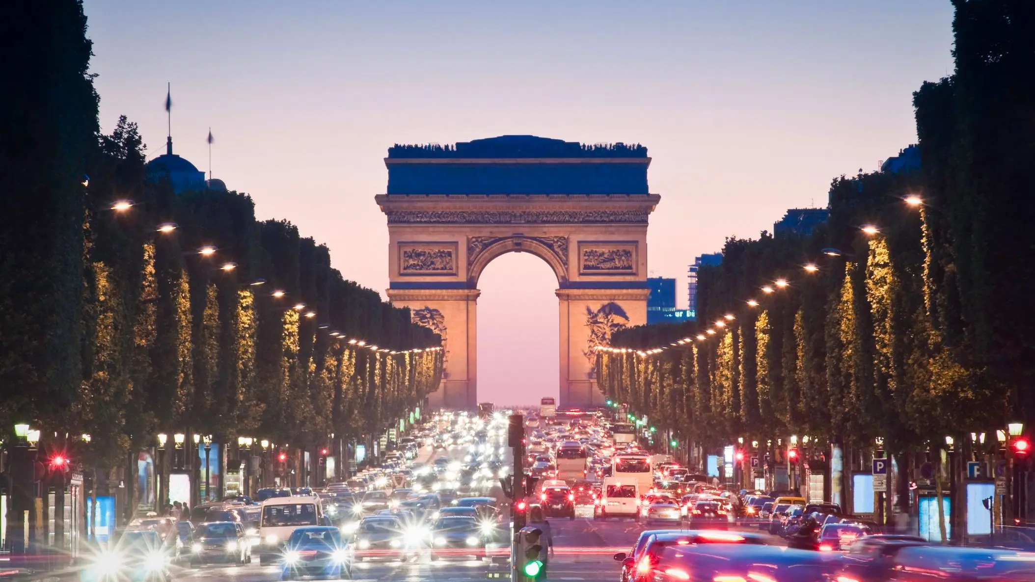 Pretty night time illuminations of the impressive Arc de Triomphe along the famous tree-lined Avenue of Champs-Elysees in Paris.