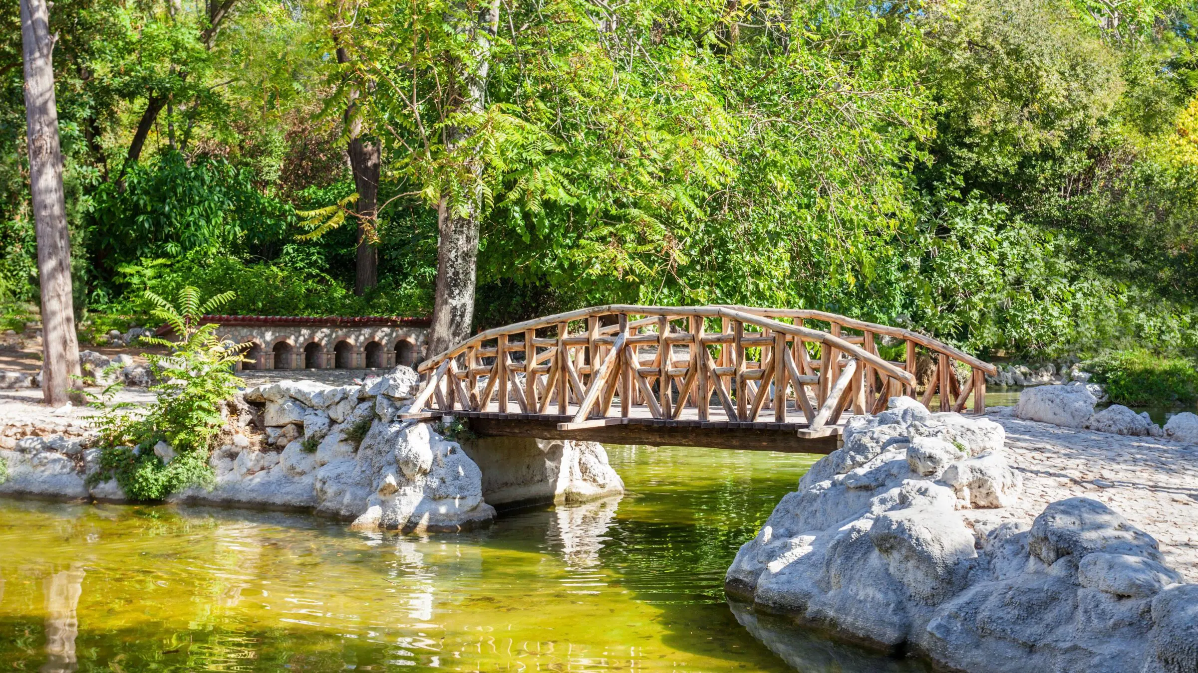 A small wooden bridge over an artificial pond in a garden.
