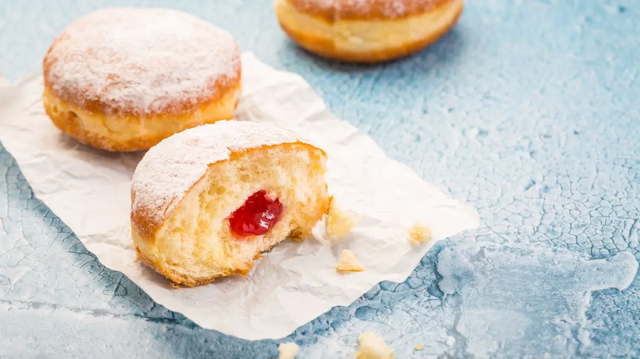 German donuts filled with strawberry jam and topped with icing sugar.