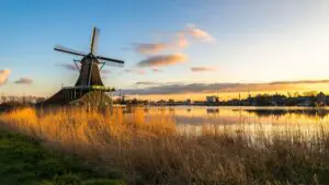 A traditional windmill in the Dutch countryside at sunset.
